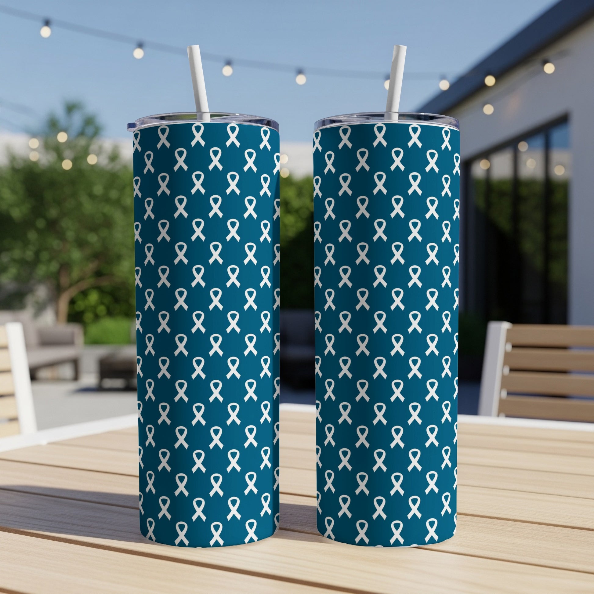 Two teal tumblers with a white ribbon pattern, each with a white straw.