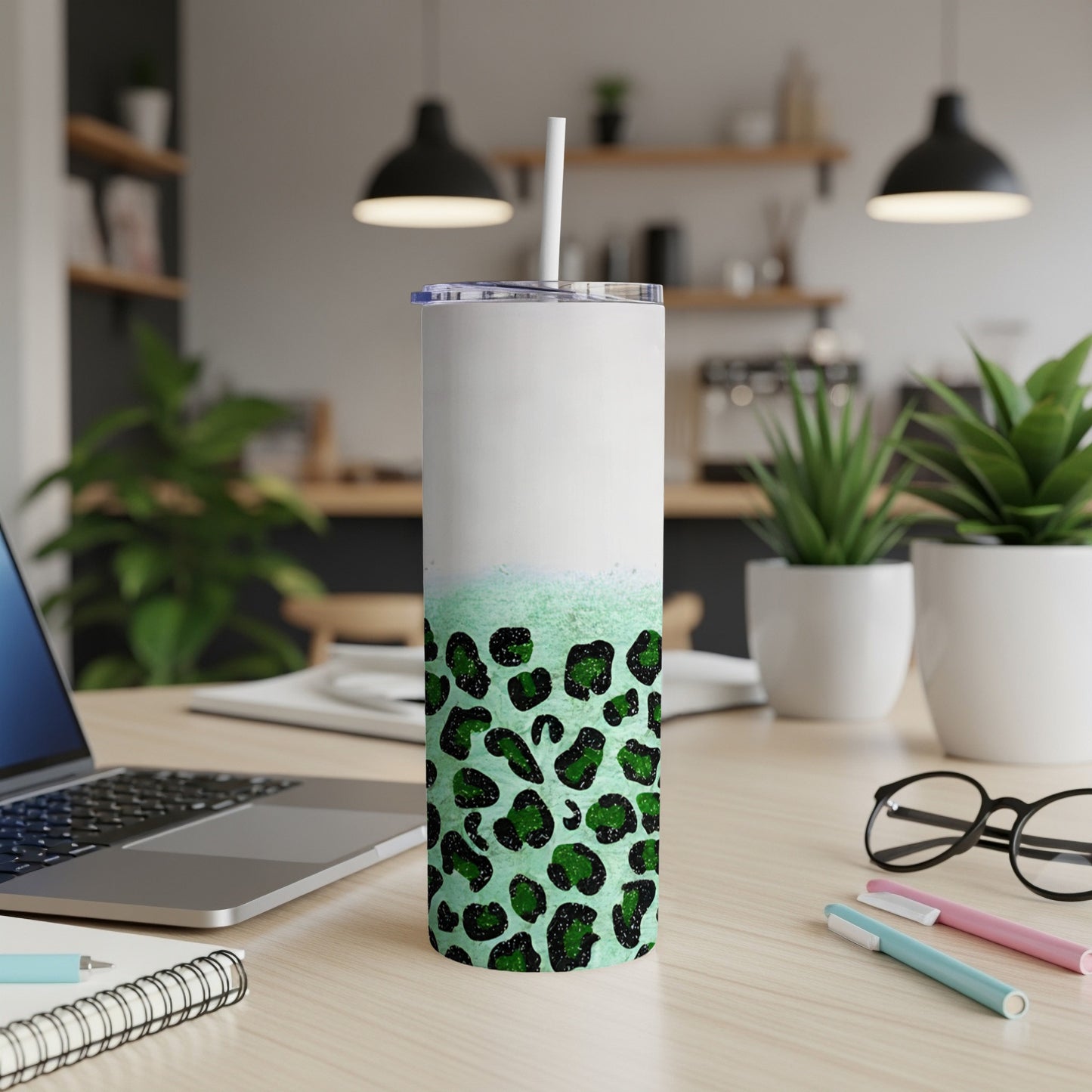 White and green leopard print tumbler with straw on desk.