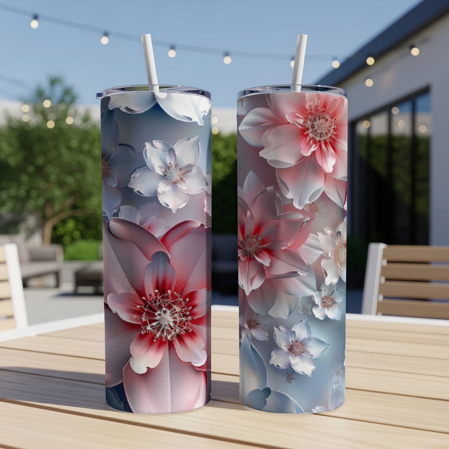 Two floral patterned tumblers on a wooden table outdoors.