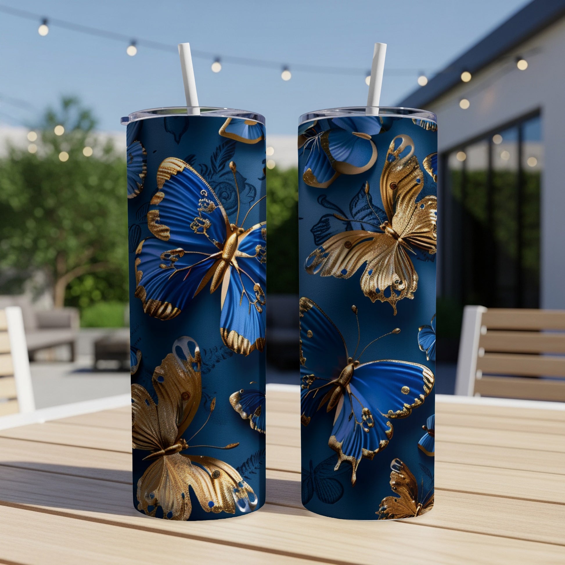 Two blue and gold butterfly patterned tumblers on a wooden table outdoors.