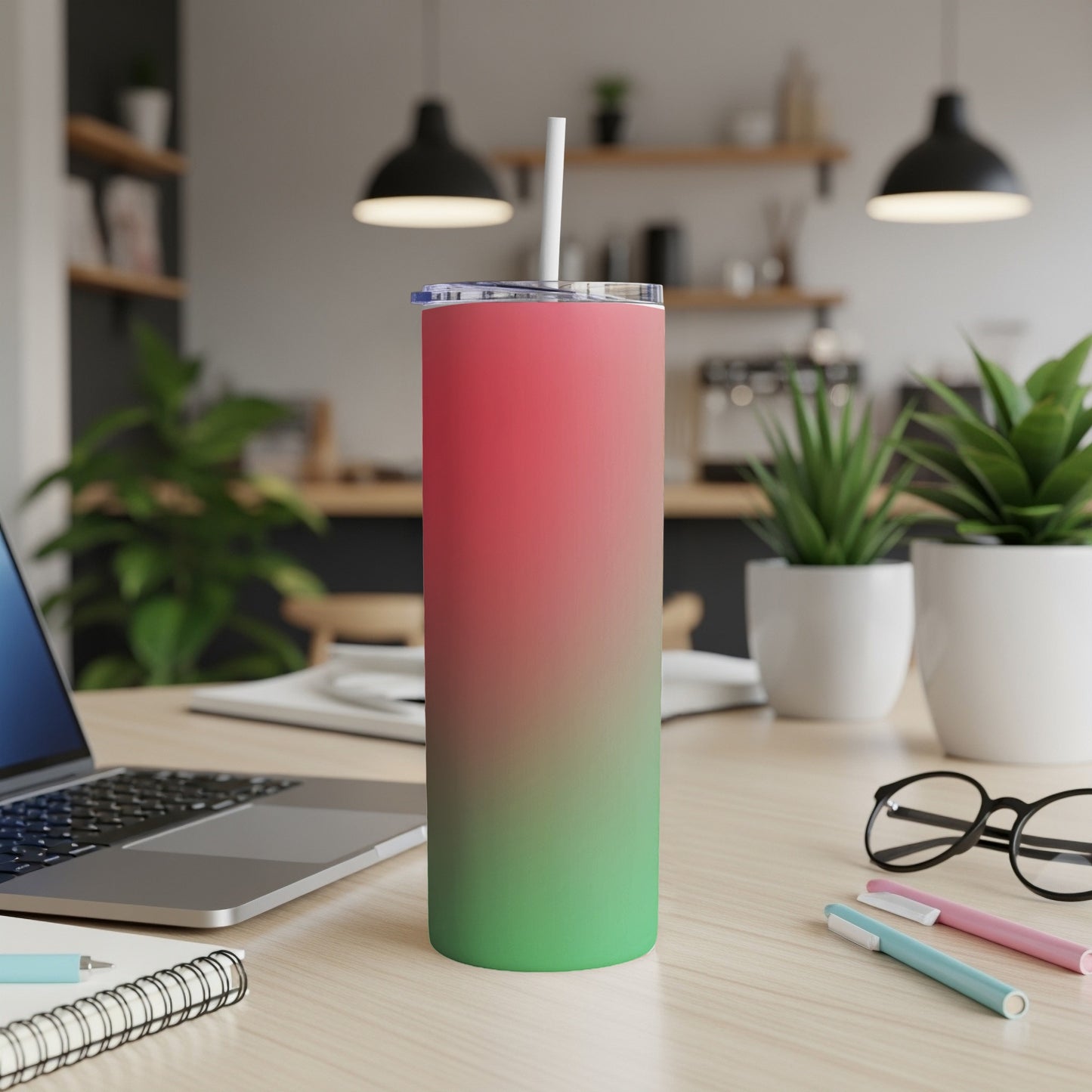 Pink and green gradient tall tumbler with straw on a desk.