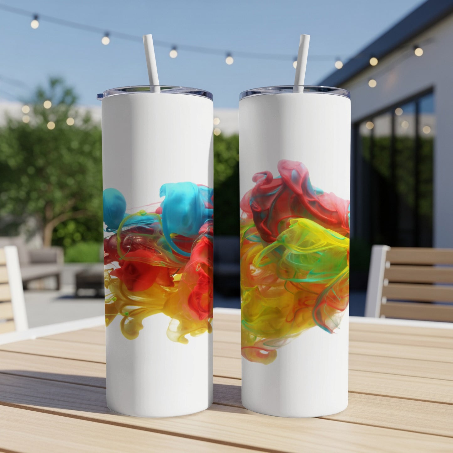 Two white tumblers with colorful ink swirls on an outdoor table.