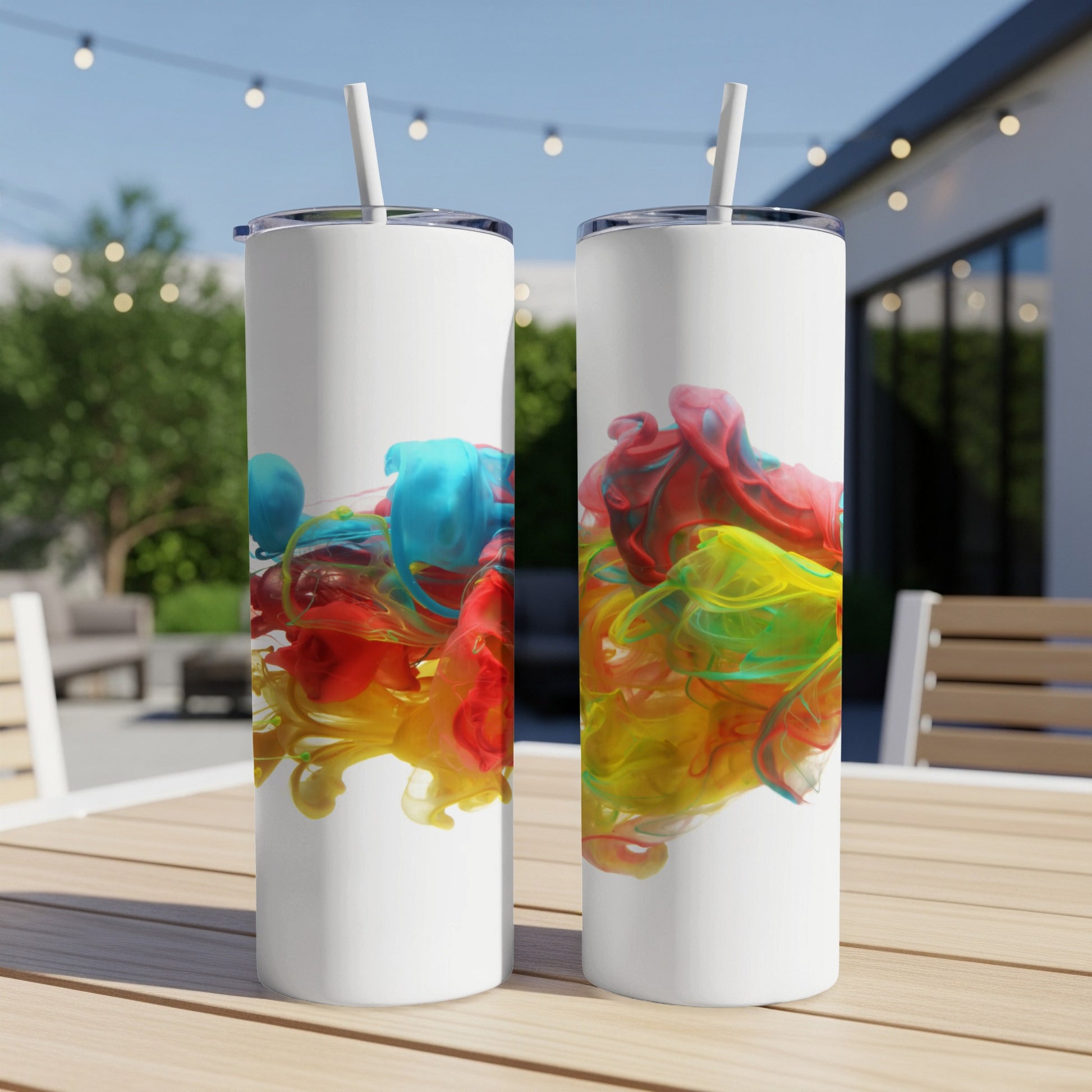 Two white tumblers with colorful ink swirls on an outdoor table.