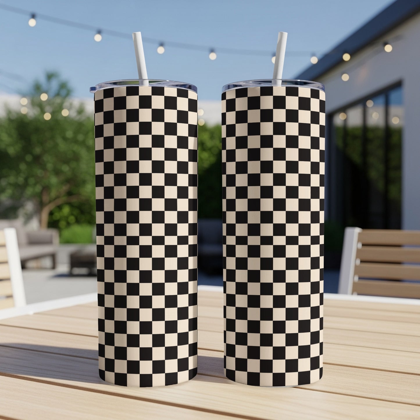 Two tall tumblers with a black and white checkerboard pattern and white straws.