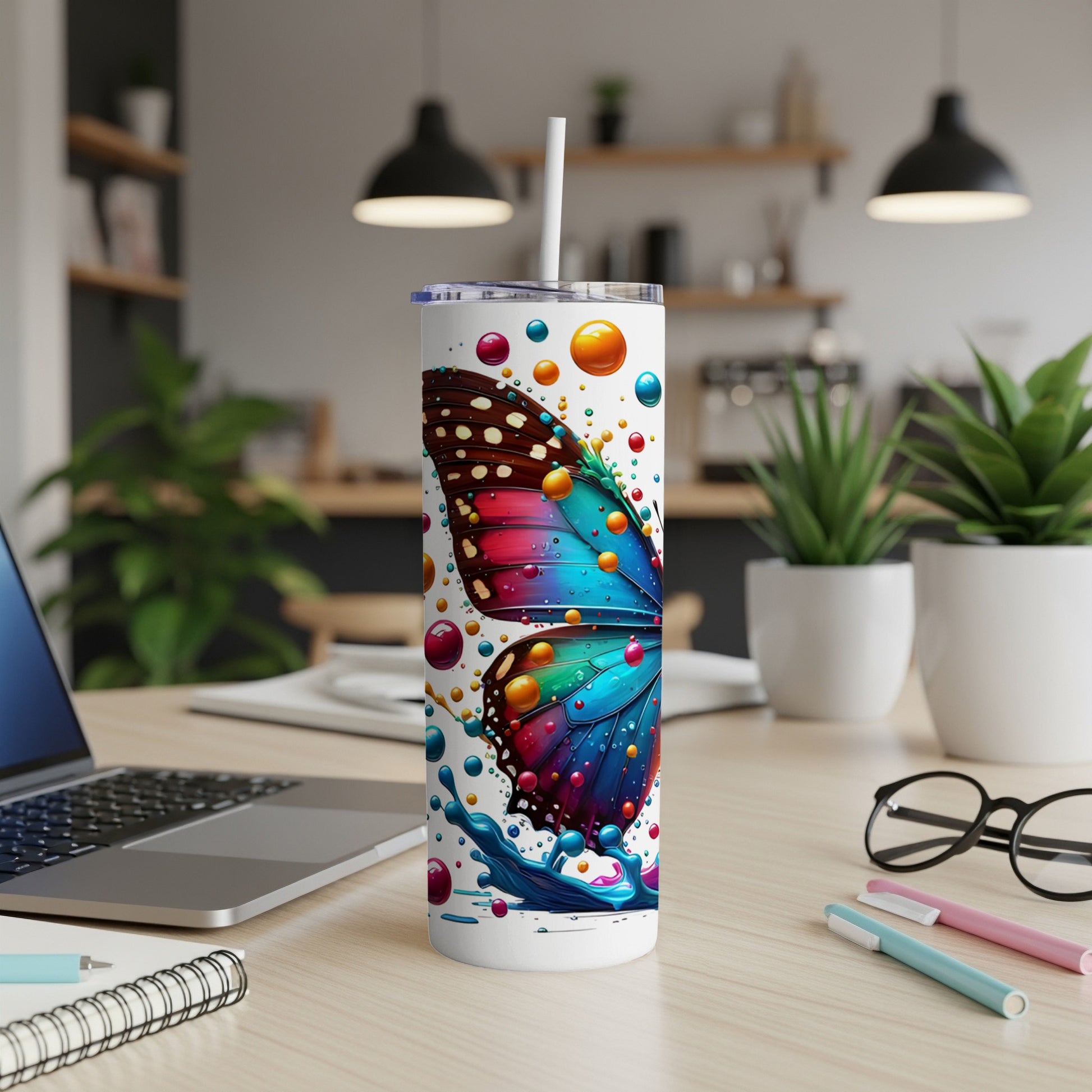 White tumbler with colorful butterfly and paint splatter design.
