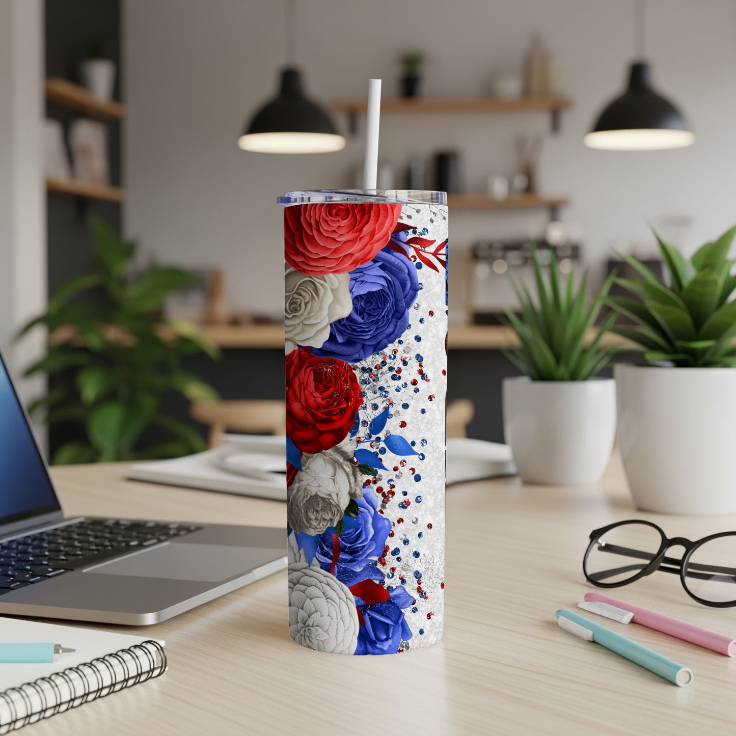 White tumbler with red, white, and blue floral design and glitter.