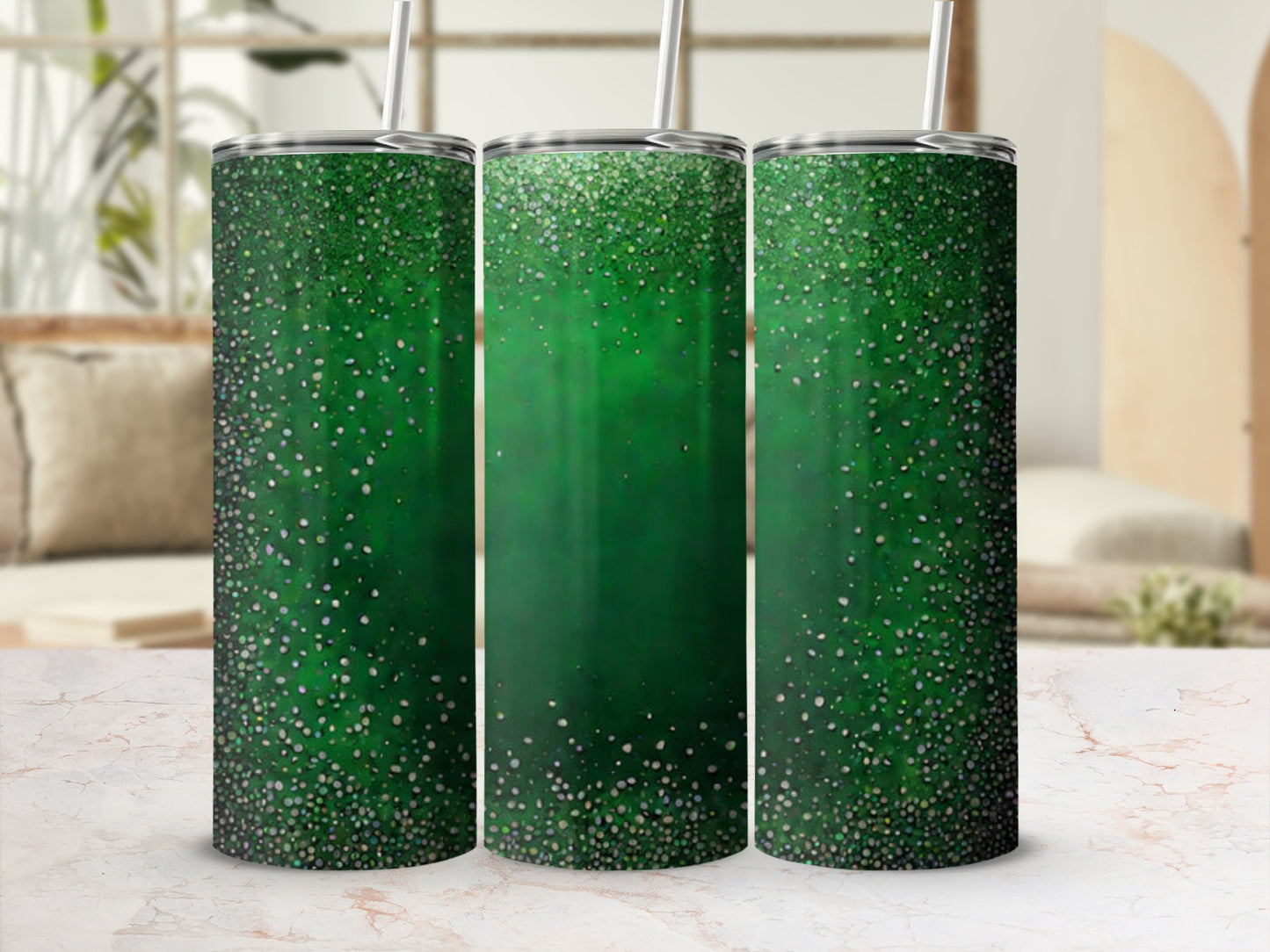Three green glitter tumblers with reusable straws on a marbled surface.