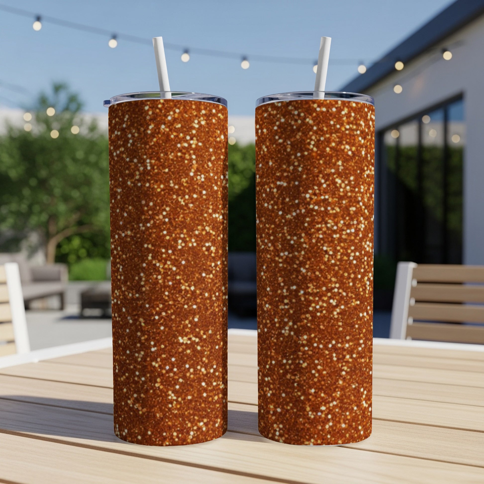 Two tall tumblers with a bronze glitter design sit on a wooden table.