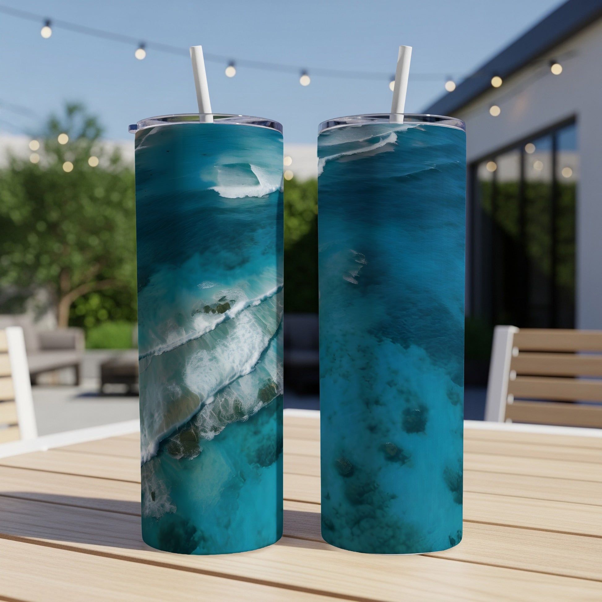 Two tumblers with aerial ocean wave and coral reef designs on a table.