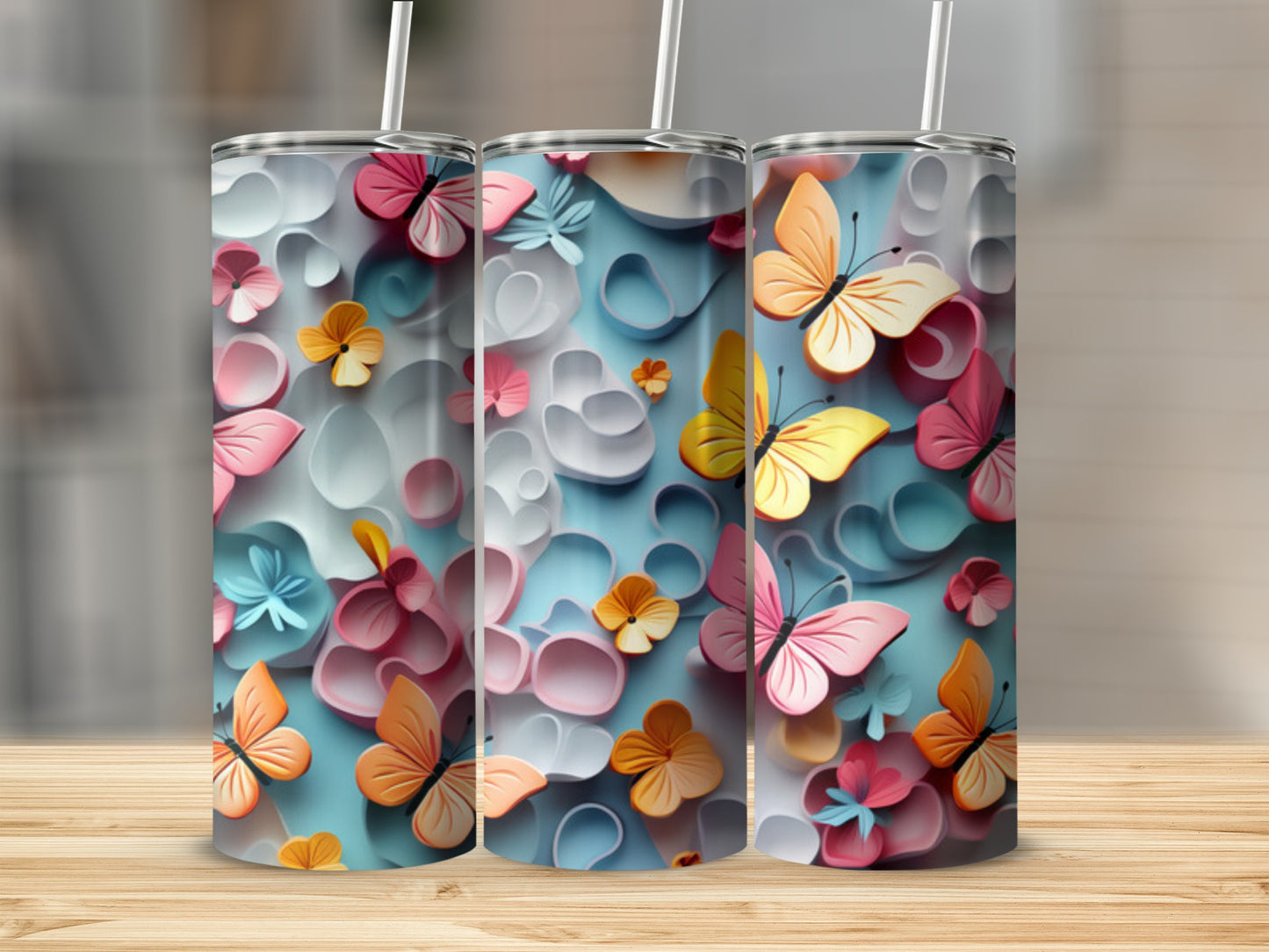Three tumblers with pastel butterflies and floral designs on a wooden surface.