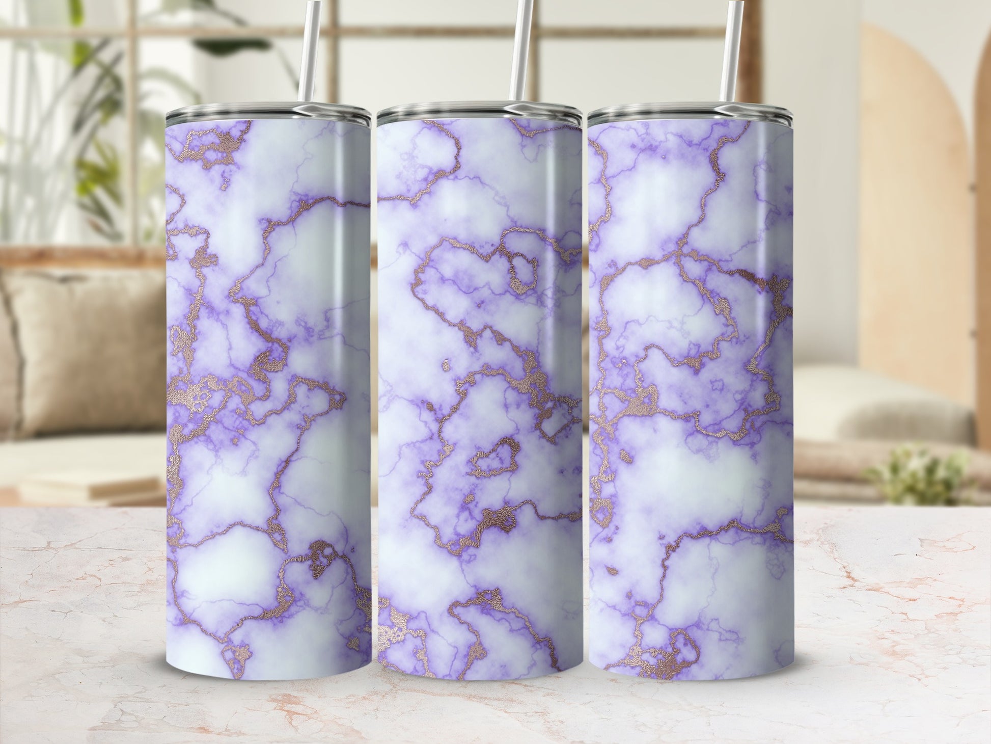 Three purple and gold marble tumblers with straws on a marble surface.