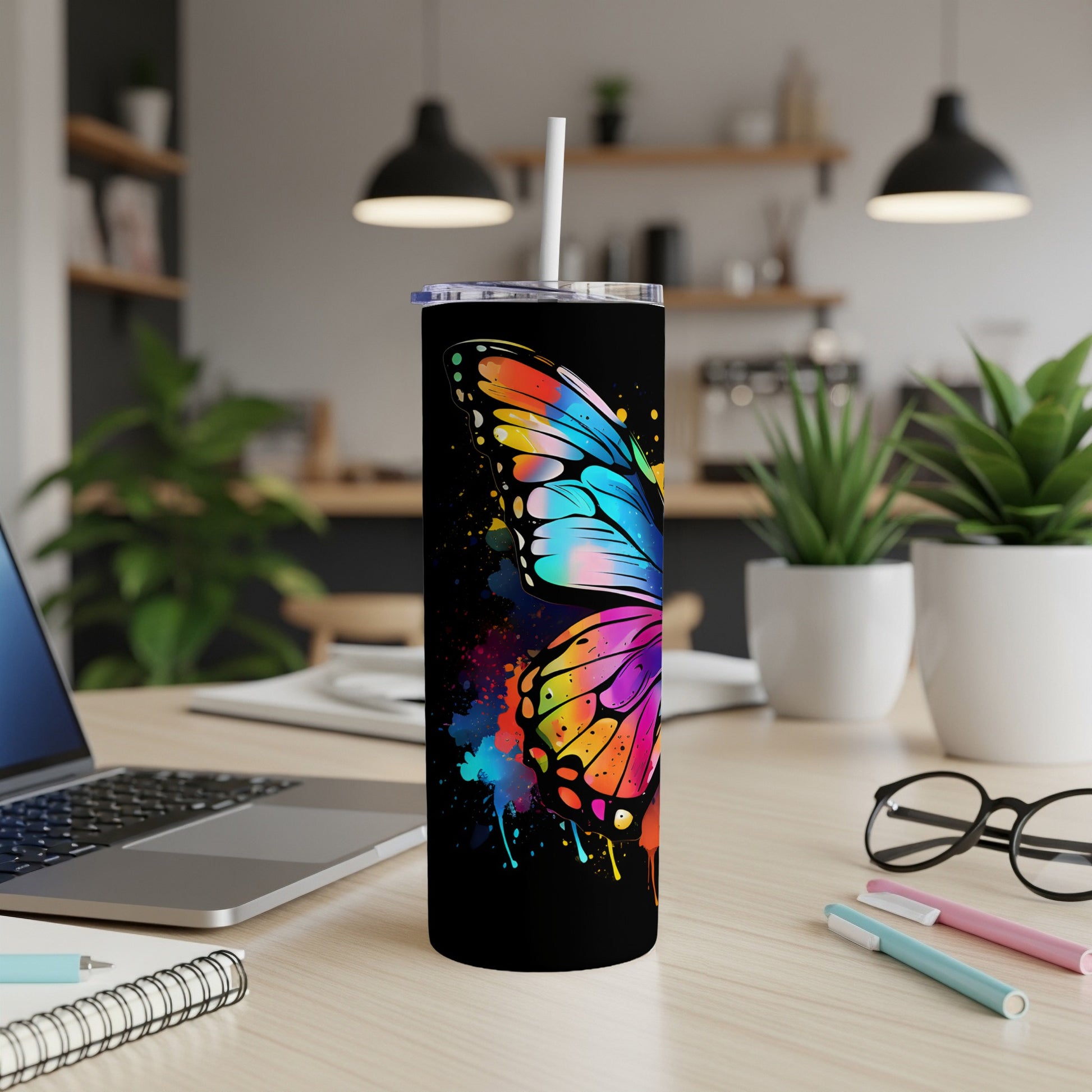 Black tumbler with vibrant, abstract butterfly wing design, straw.