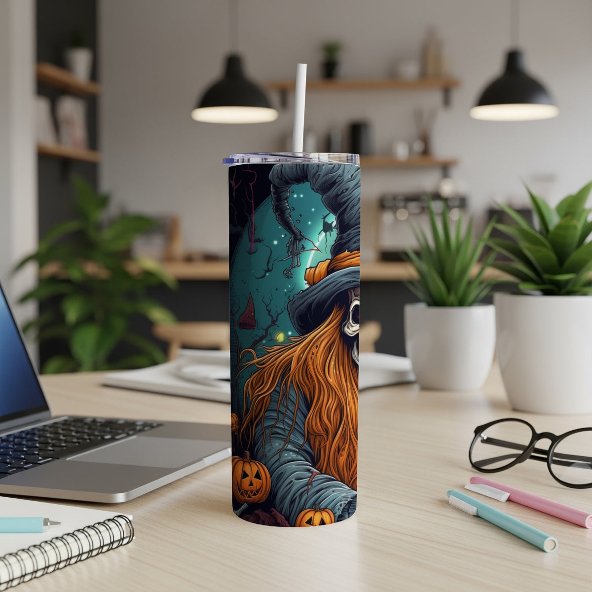 Halloween themed tumbler with skeleton witch and pumpkins on a desk.