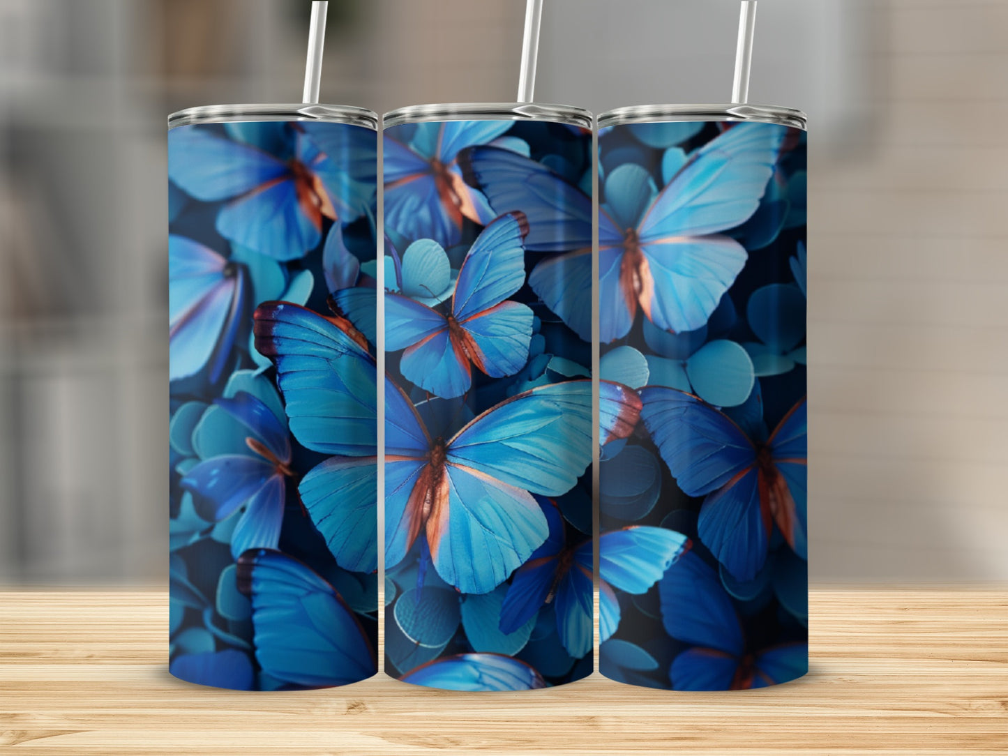 Three blue butterfly tumblers with straw on a wooden surface.
