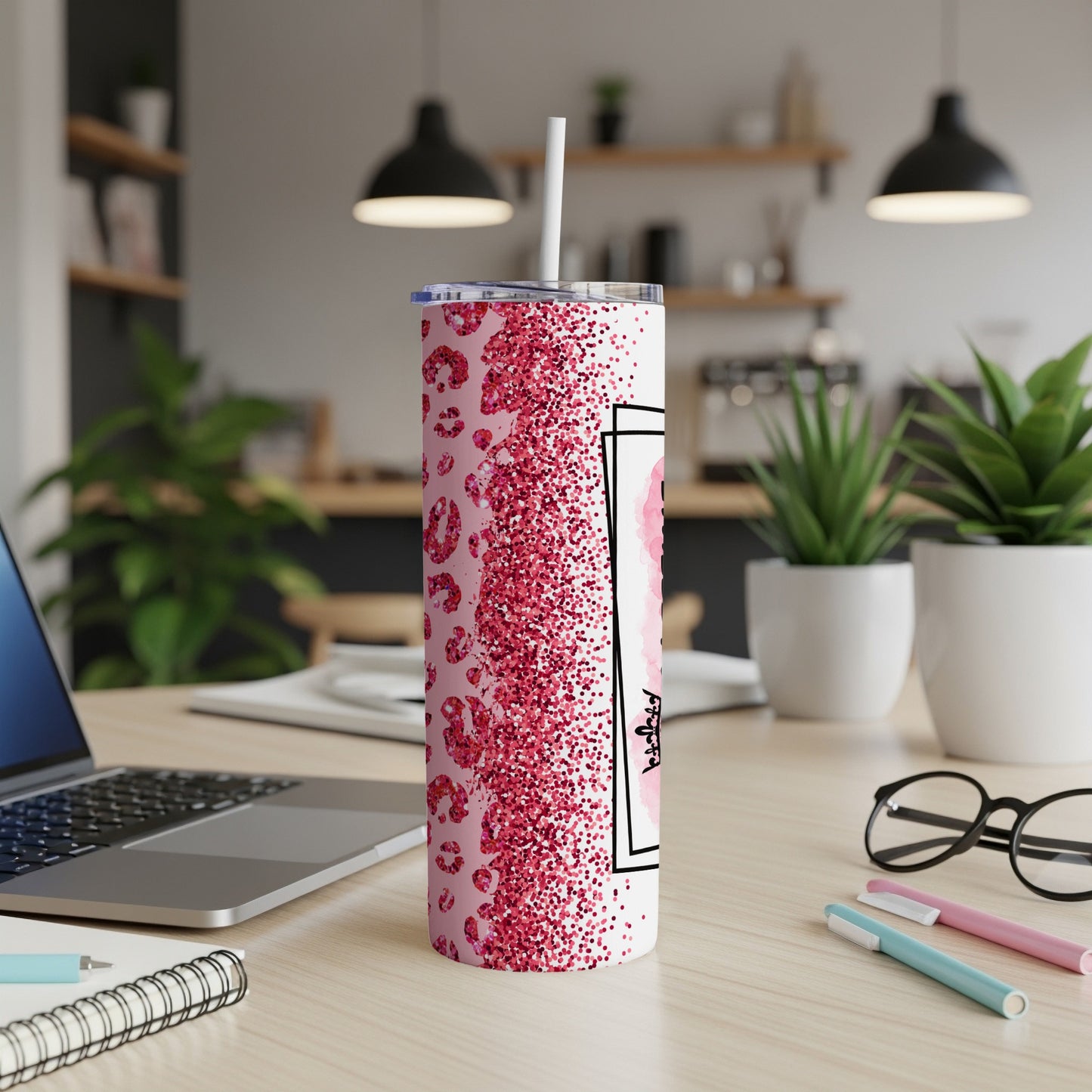 Pink glitter tumbler with a straw and a black framed name design.