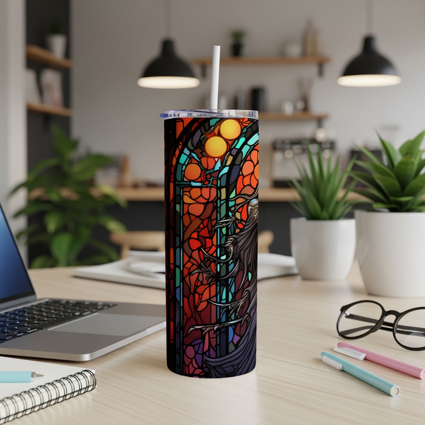 Stained glass tumbler with dragon and celestial motifs on a desk.
