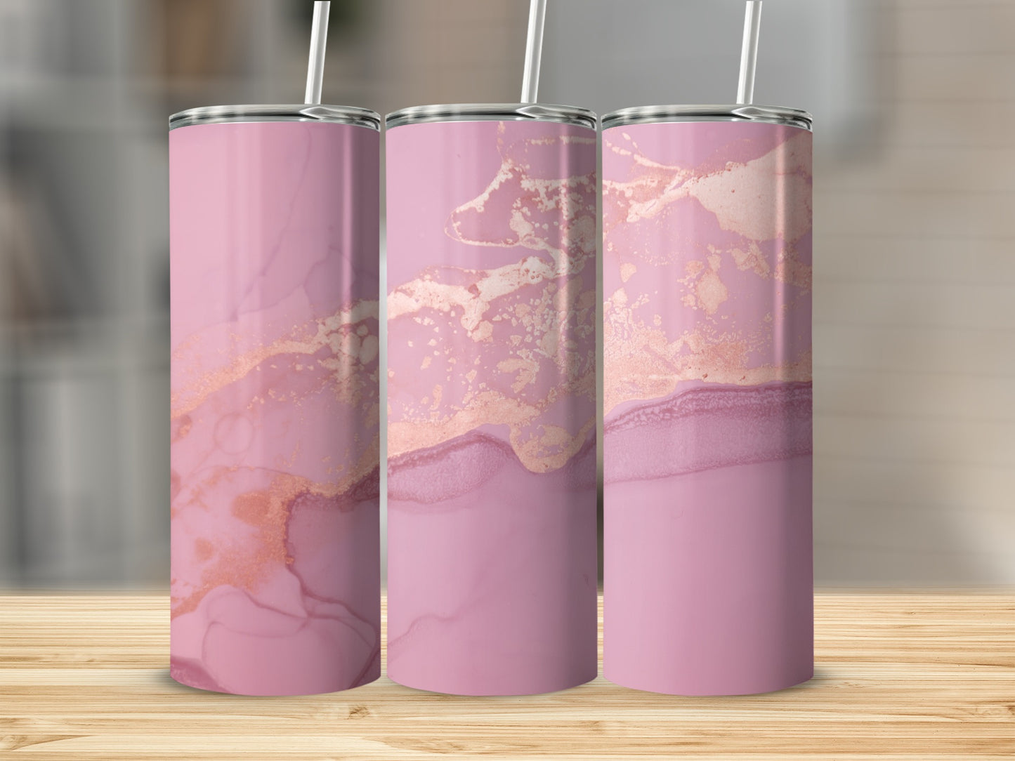 Three pink tumblers with rose gold marble pattern on wooden surface.