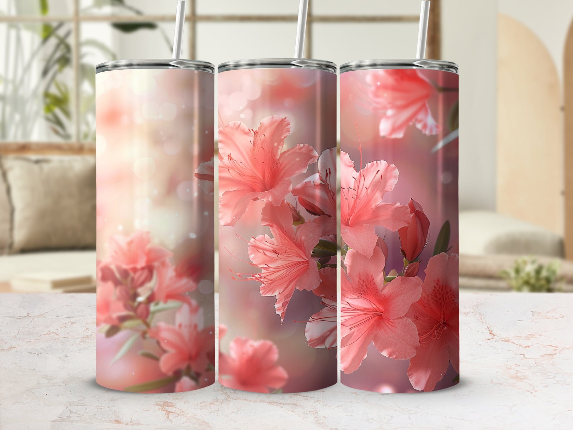 Three pink floral tumblers with straws on a patterned surface.