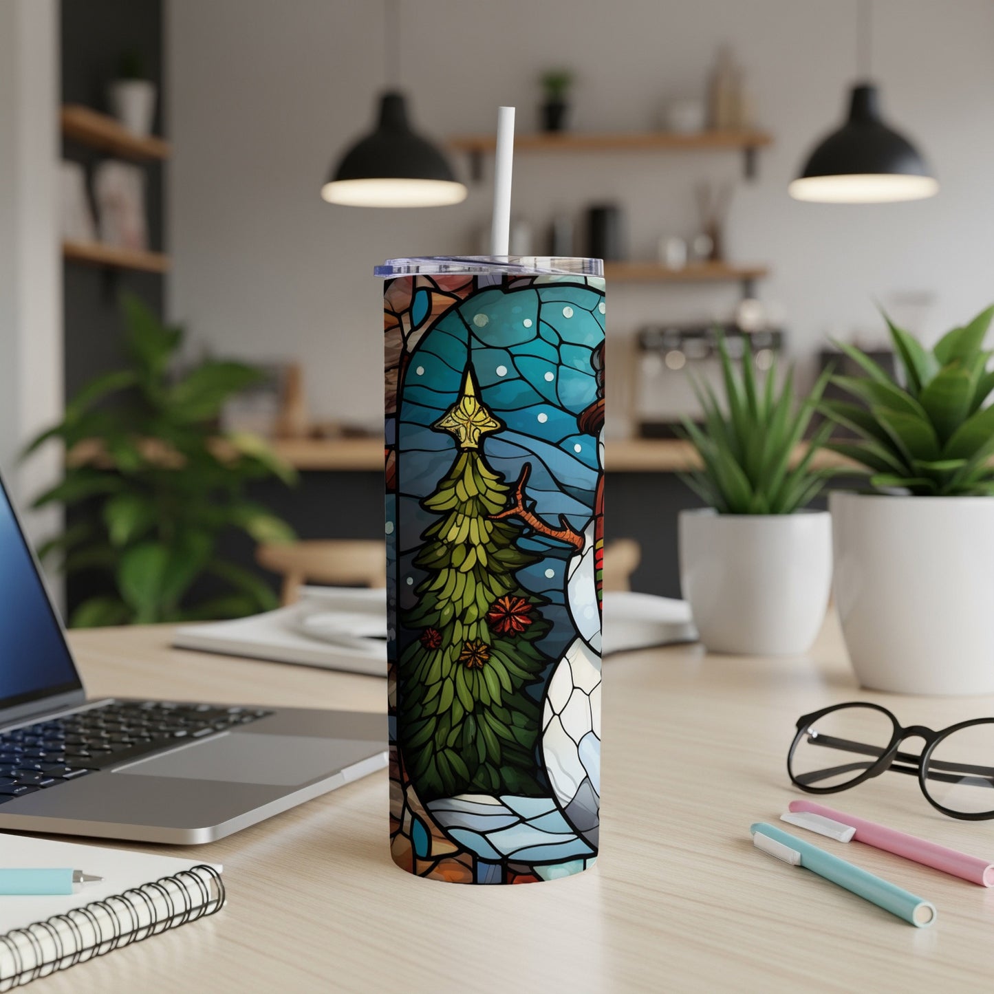 Stained glass snowman and Christmas tree tumbler with straw on desk.