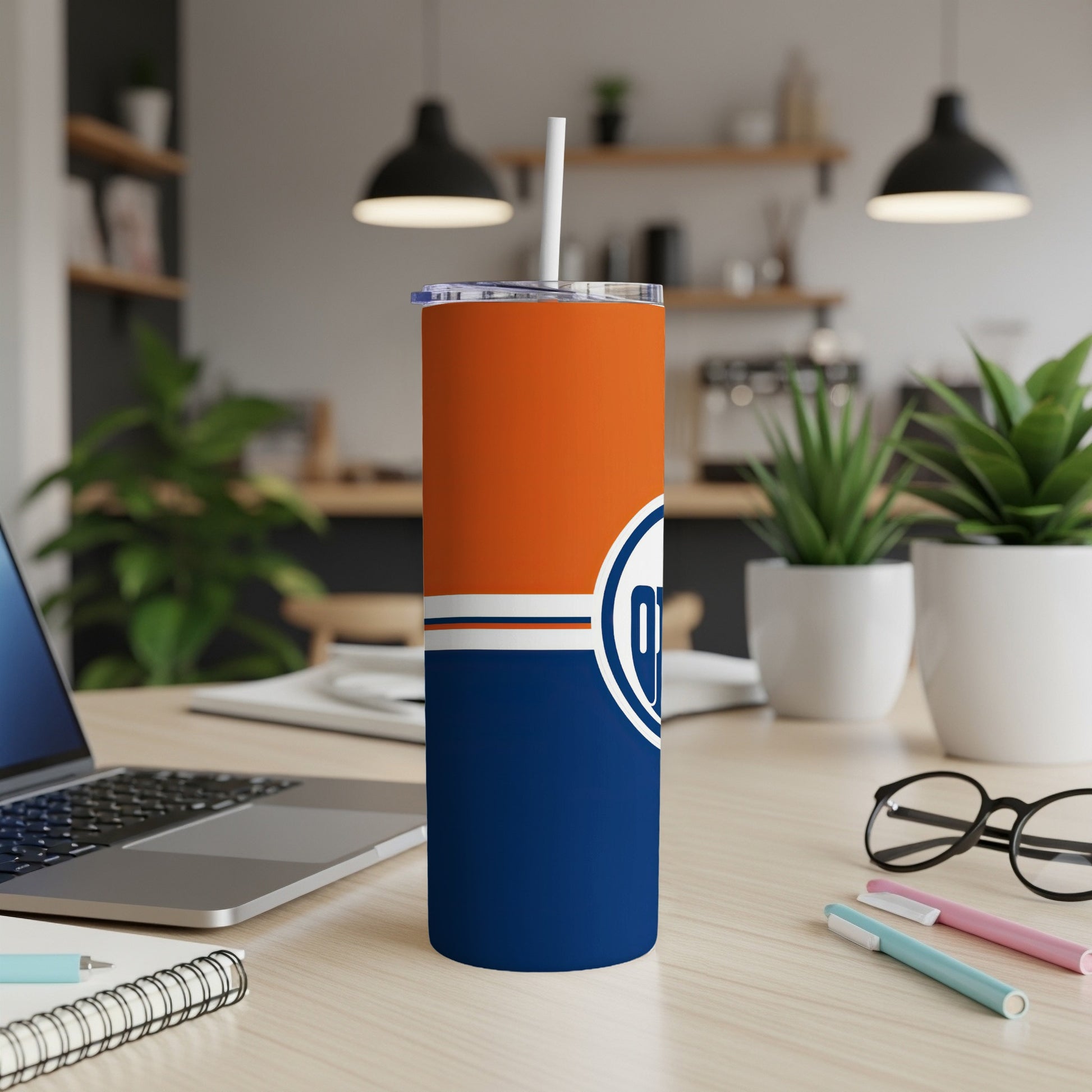 Edmonton Oilers tumbler with white straw, laptop, and eyeglasses on a desk.