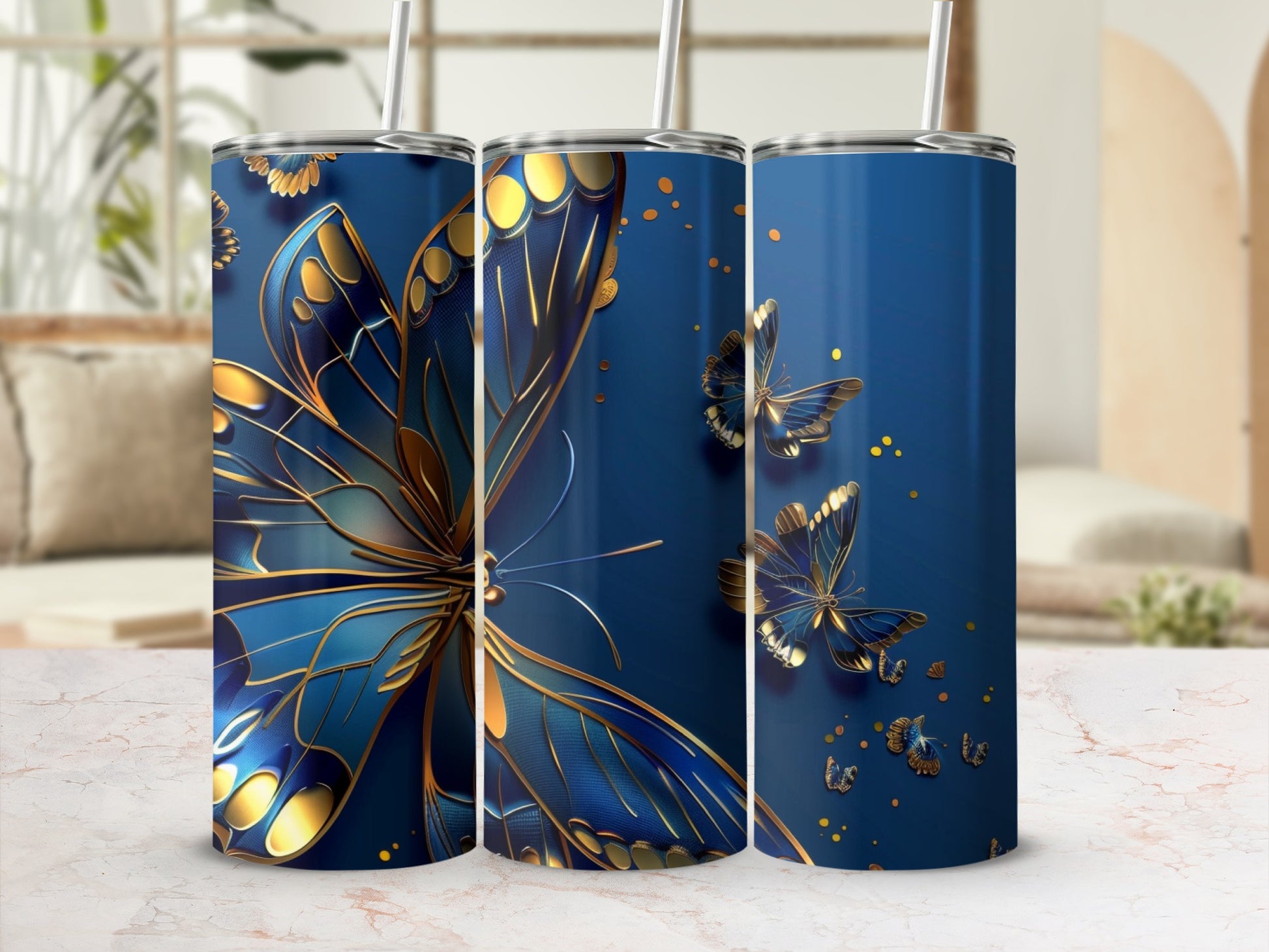 Three blue tumblers with gold butterfly designs against a blurred background.