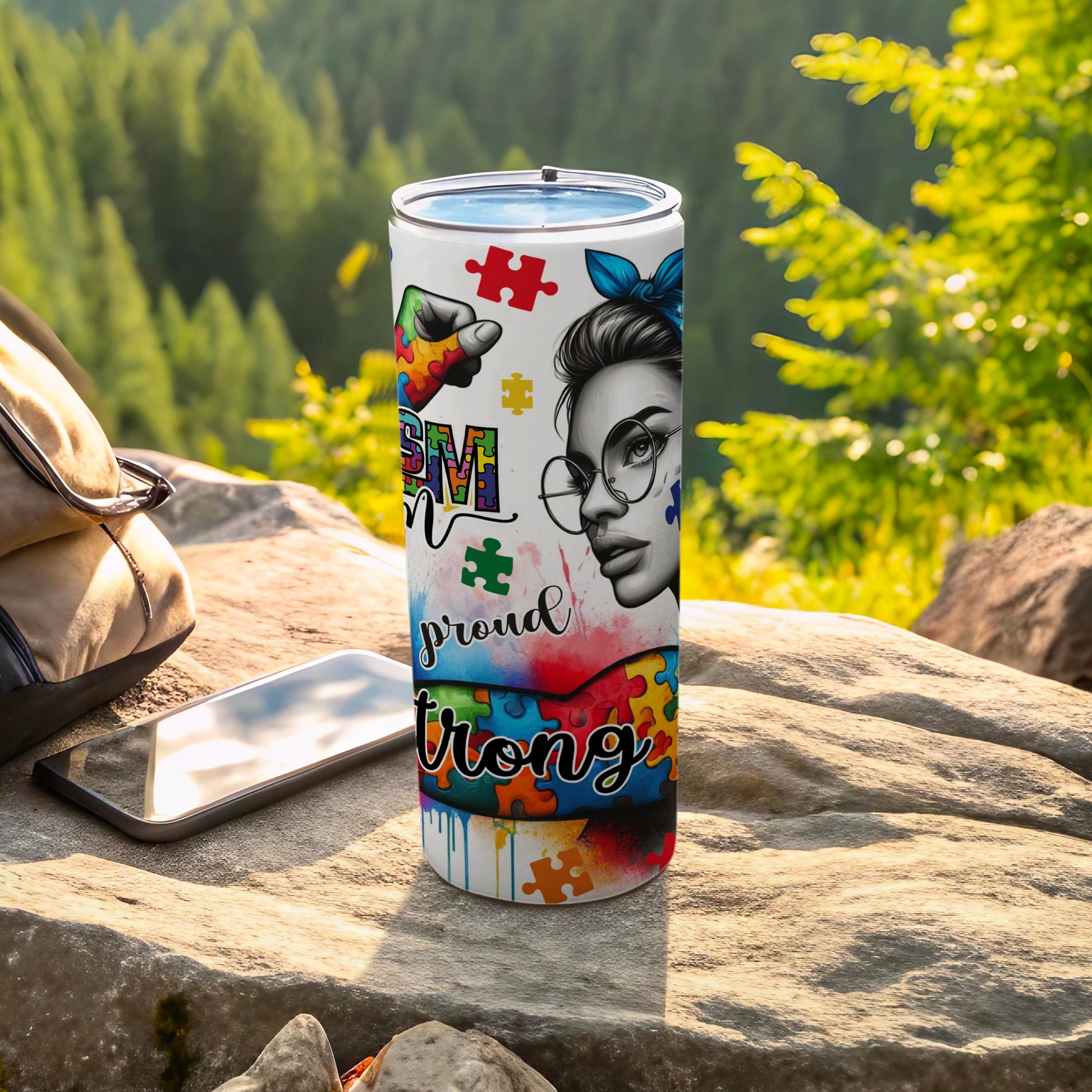 Autism awareness tumbler with puzzle pieces, a woman's face, and "proud" text.