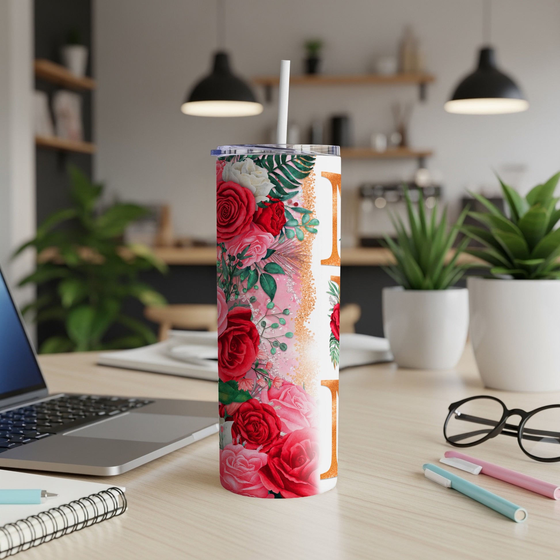 Floral tumbler with lid and straw on a desk with a laptop.