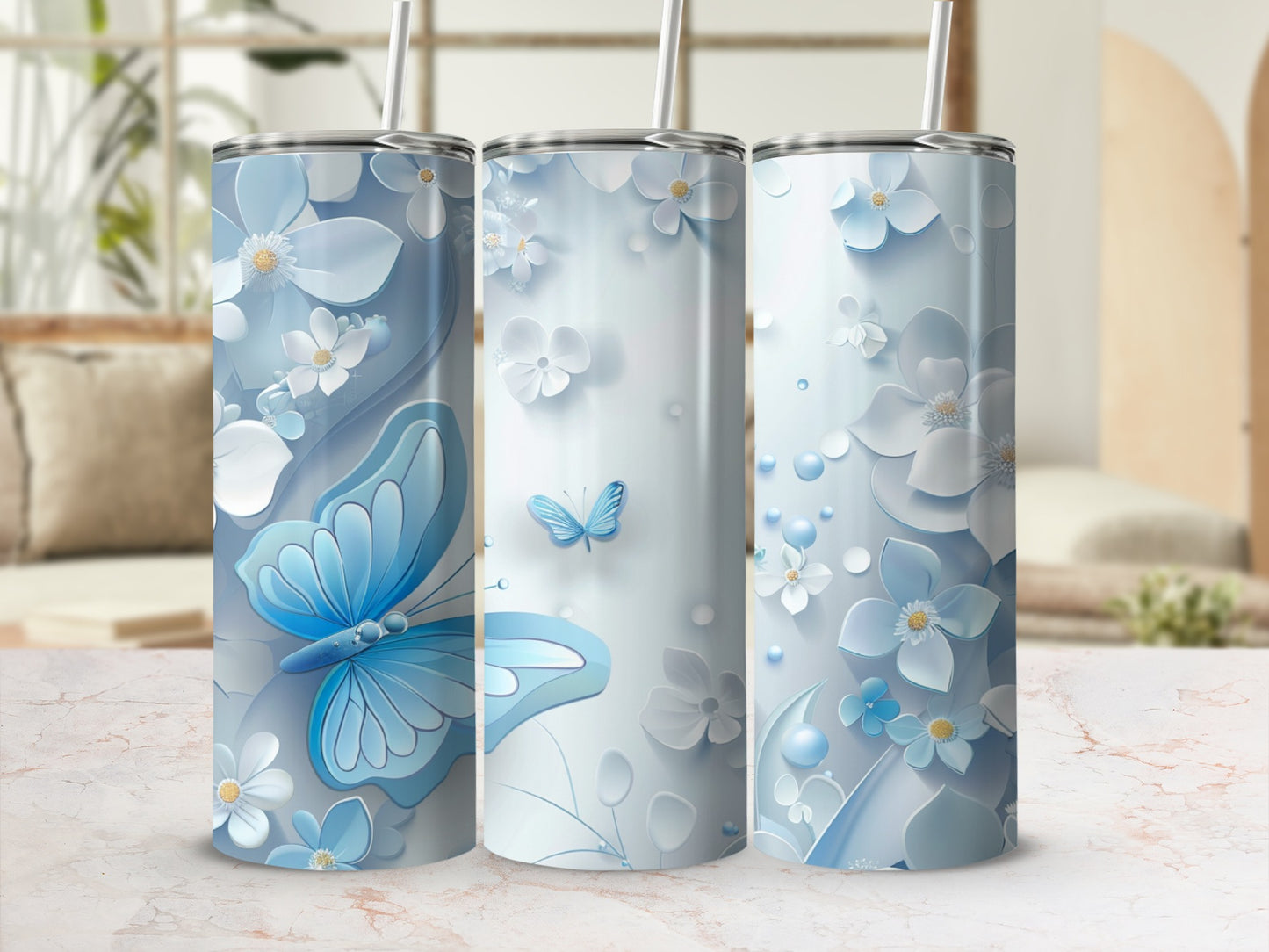 Three blue floral tumblers with butterflies and straws on a marble surface.