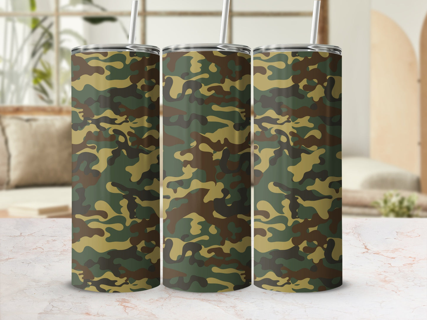 Three tumblers with camouflage pattern and metal straws on a marble surface.