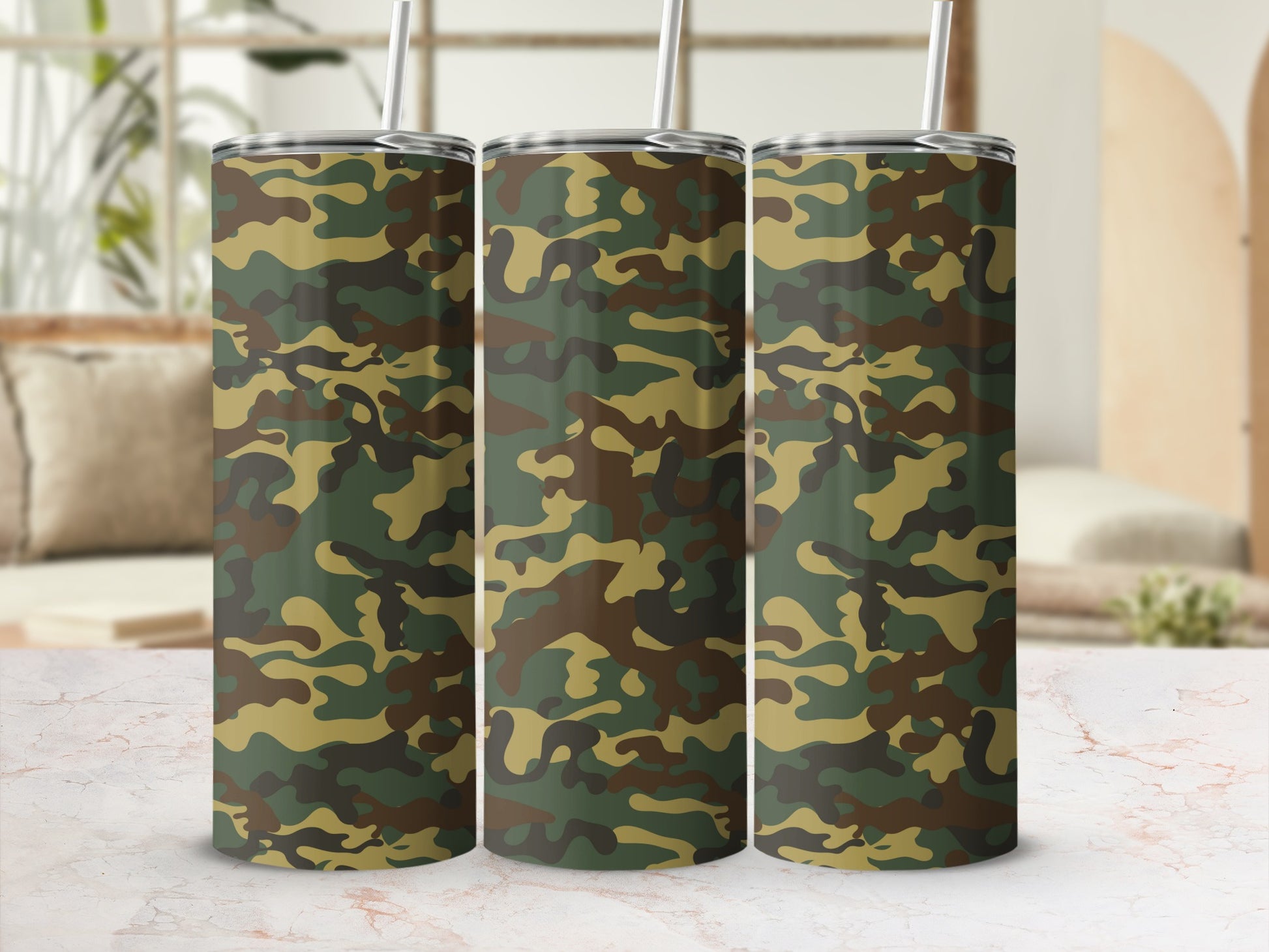 Three tumblers with camouflage pattern and metal straws on a marble surface.