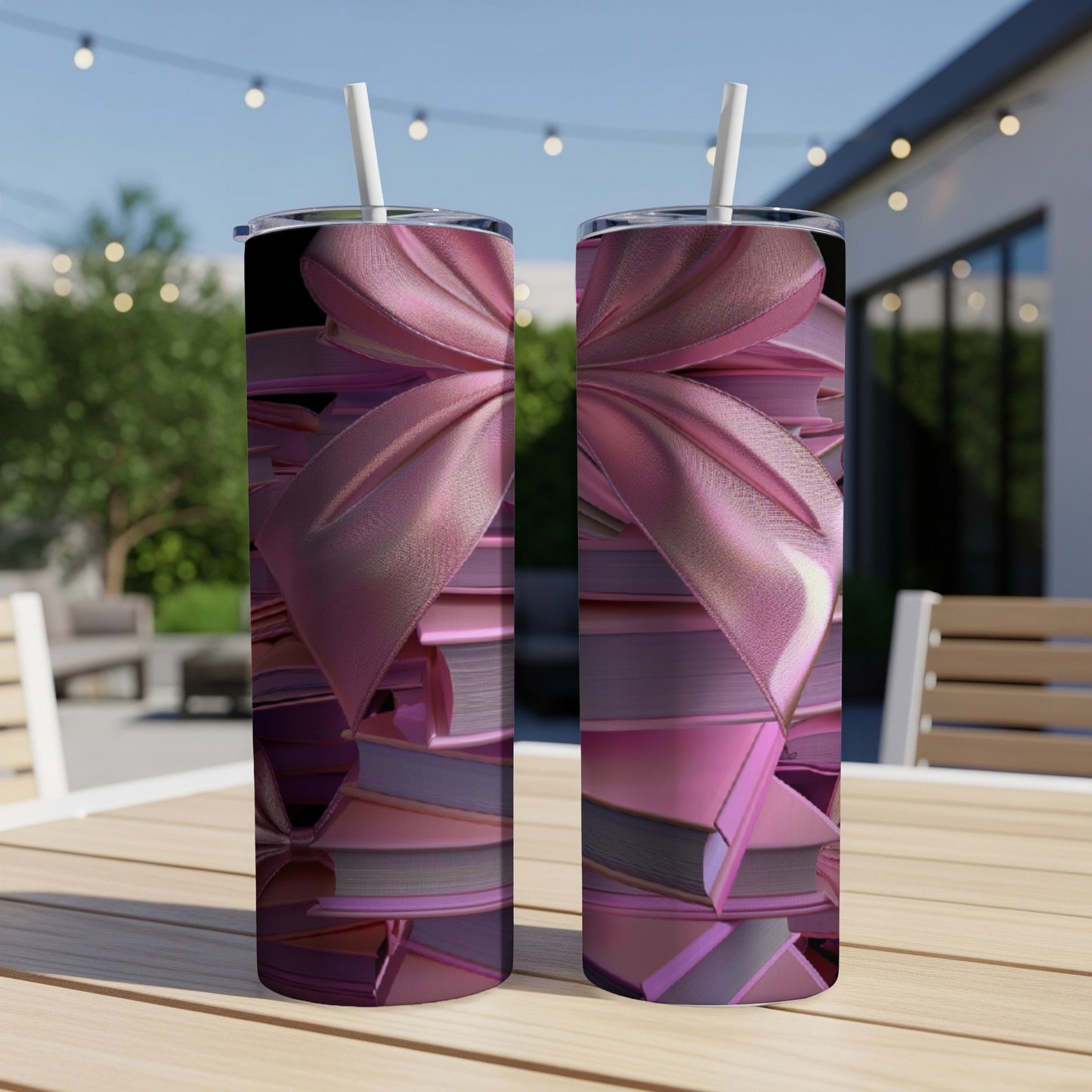 Two pink tumblers with a bow pattern sit on a table outdoors.