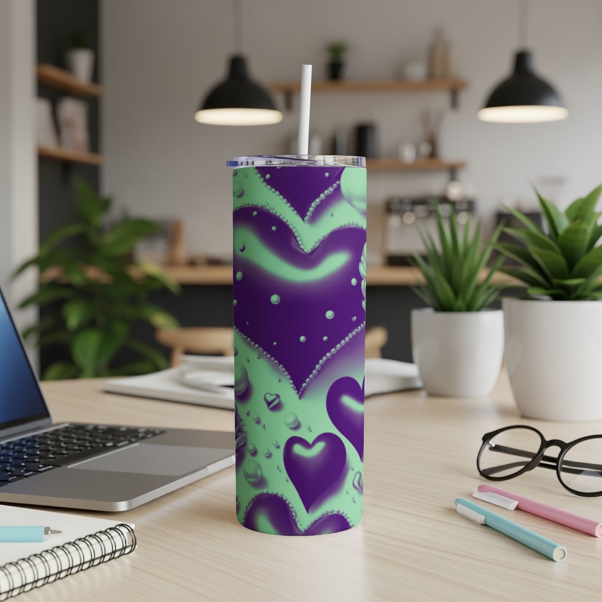 Purple and green hearts tumbler with straw on a desk.