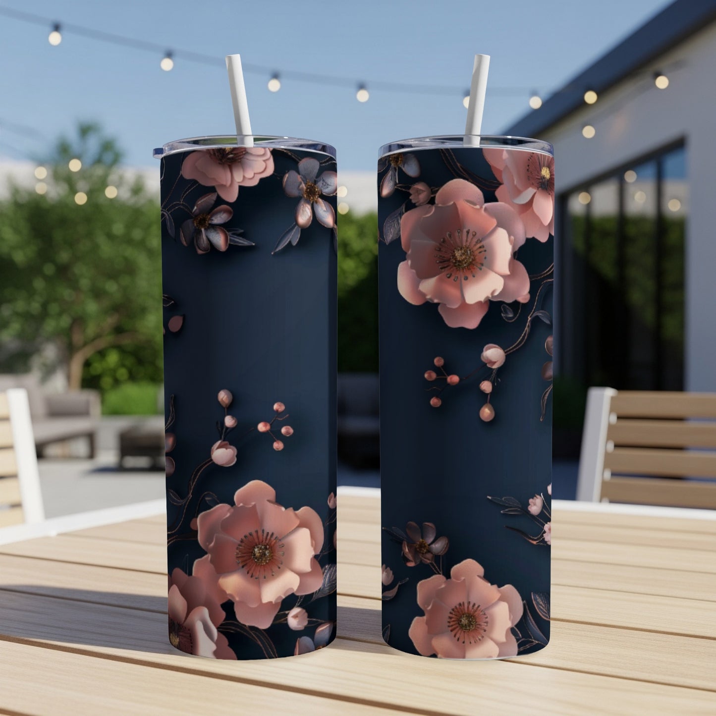 Two dark blue tumblers with rose gold floral pattern on outdoor table.