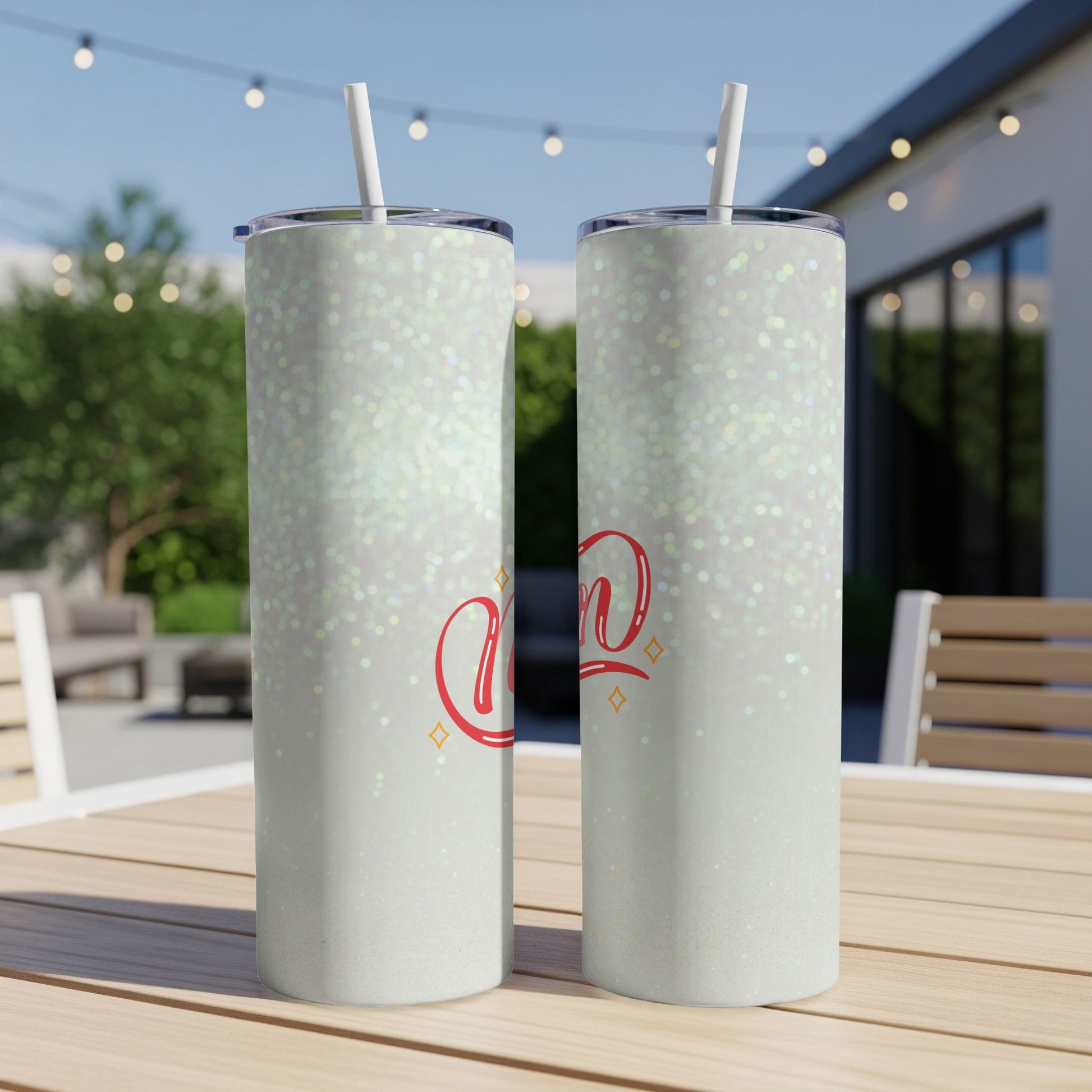 Two glitter-covered tumblers with "Mom" in red script sit on a table.