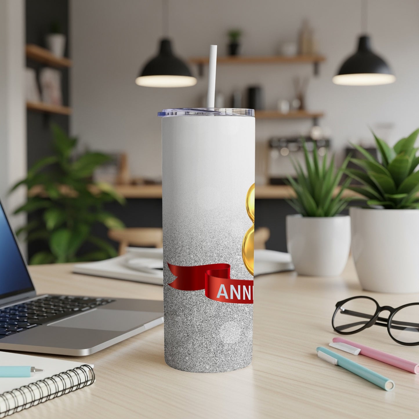 Silver tumbler with "8th ANNIVERSARY" text and red ribbon on desk.