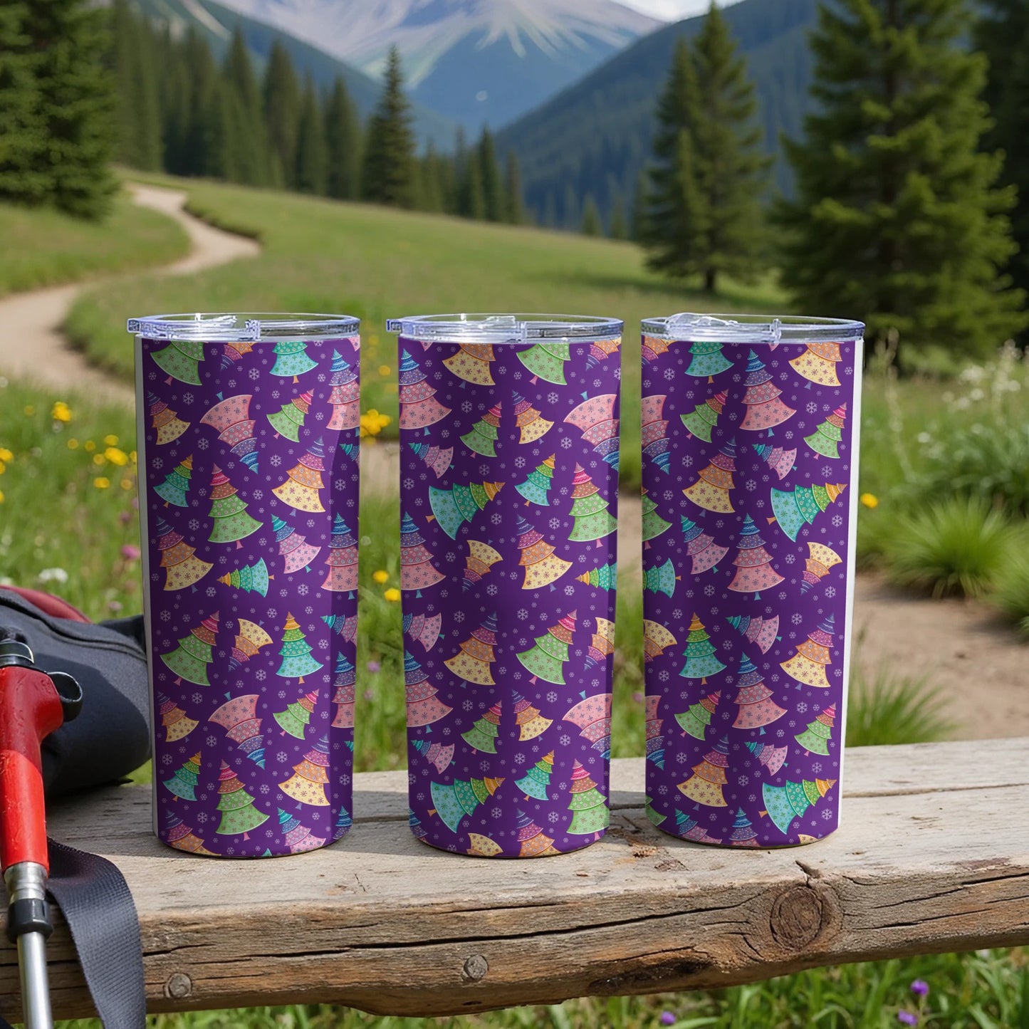 Three tumblers with a purple Christmas tree pattern sit on a wooden surface.