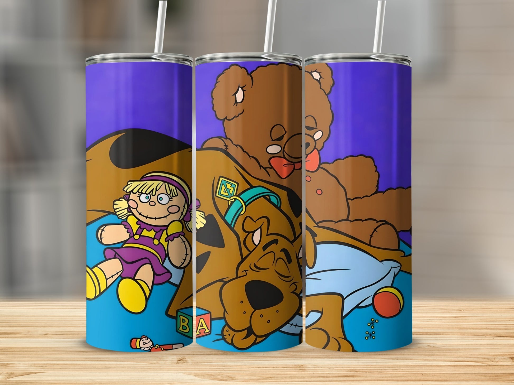 Scooby-Doo and a doll sitting with a teddy bear on a blue pillow.