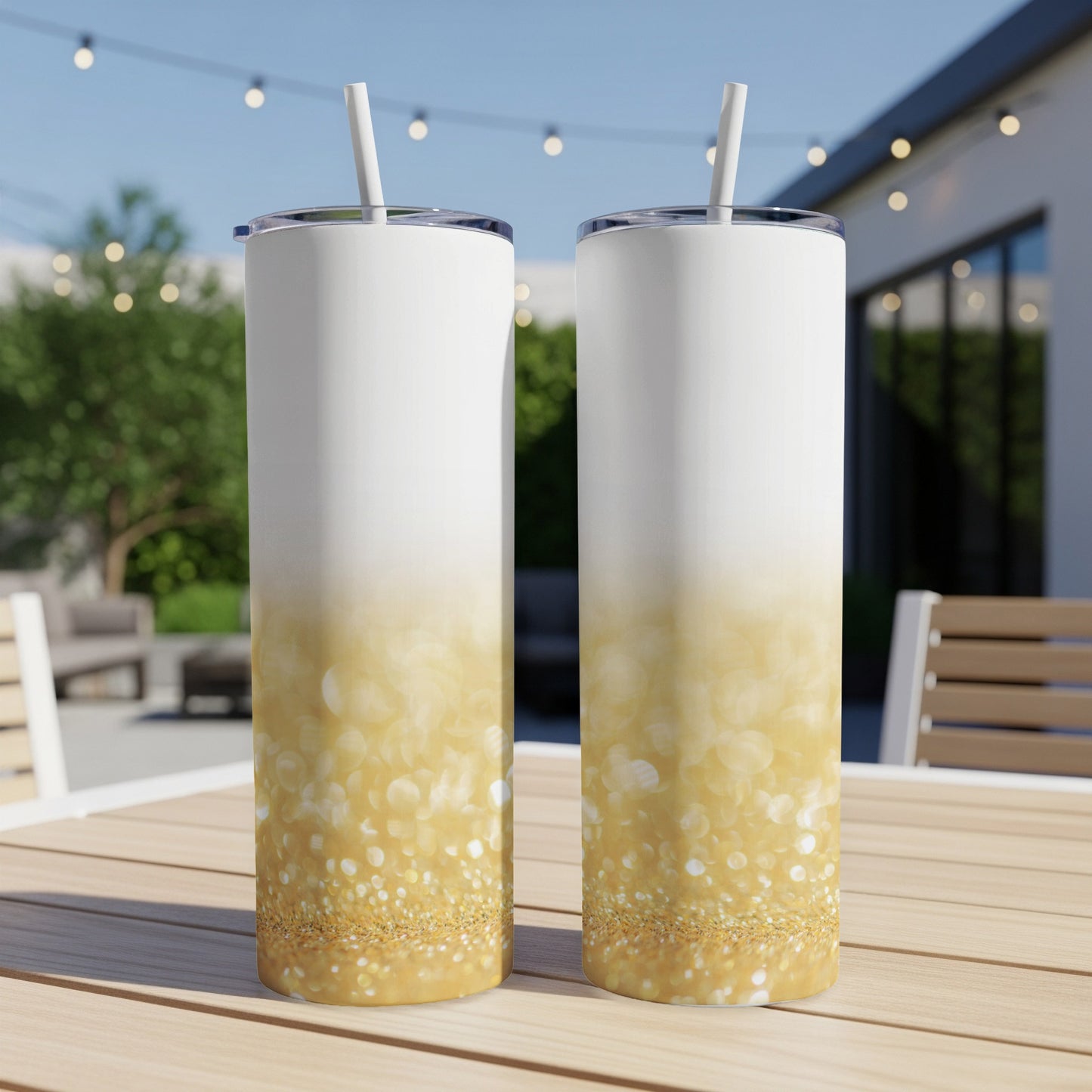 Two tall white tumblers with gold glitter gradient design on a table.