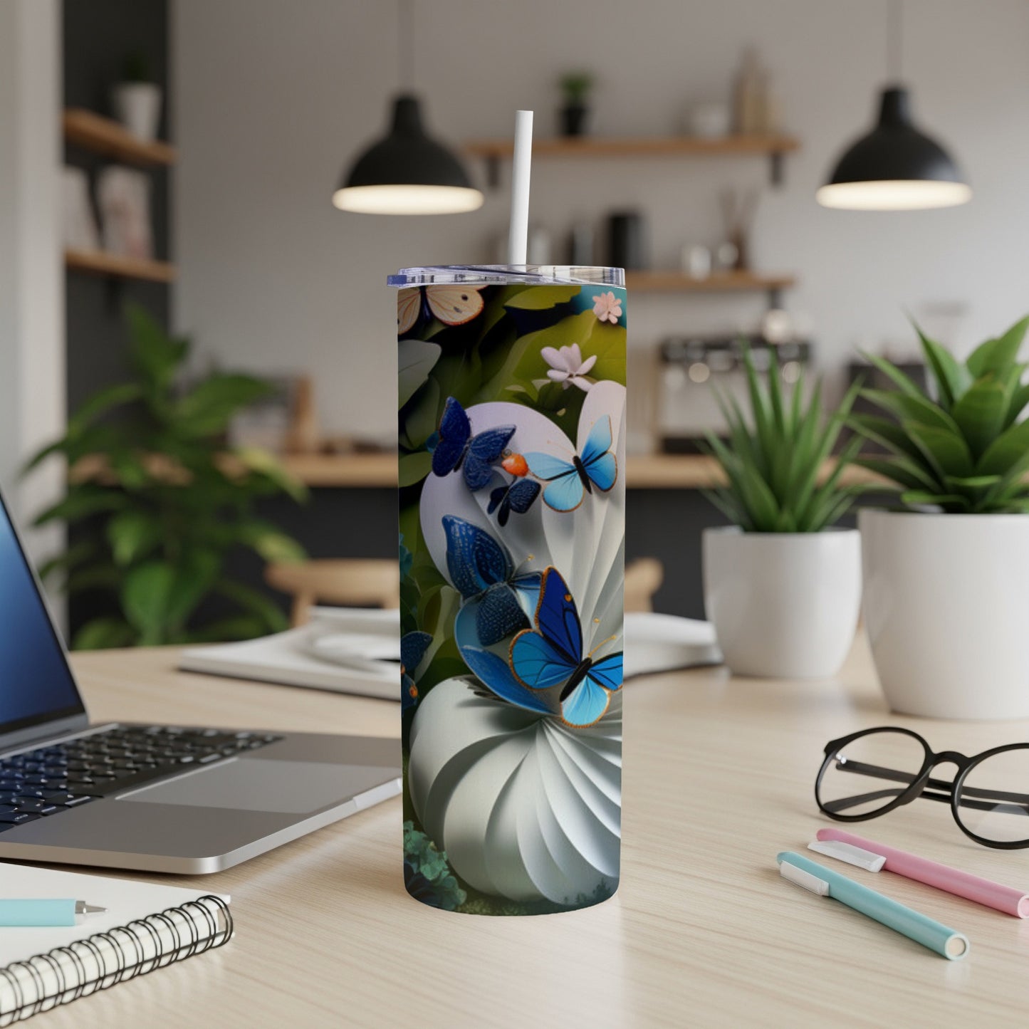 Tall tumbler with blue butterflies and floral accents on a desk.