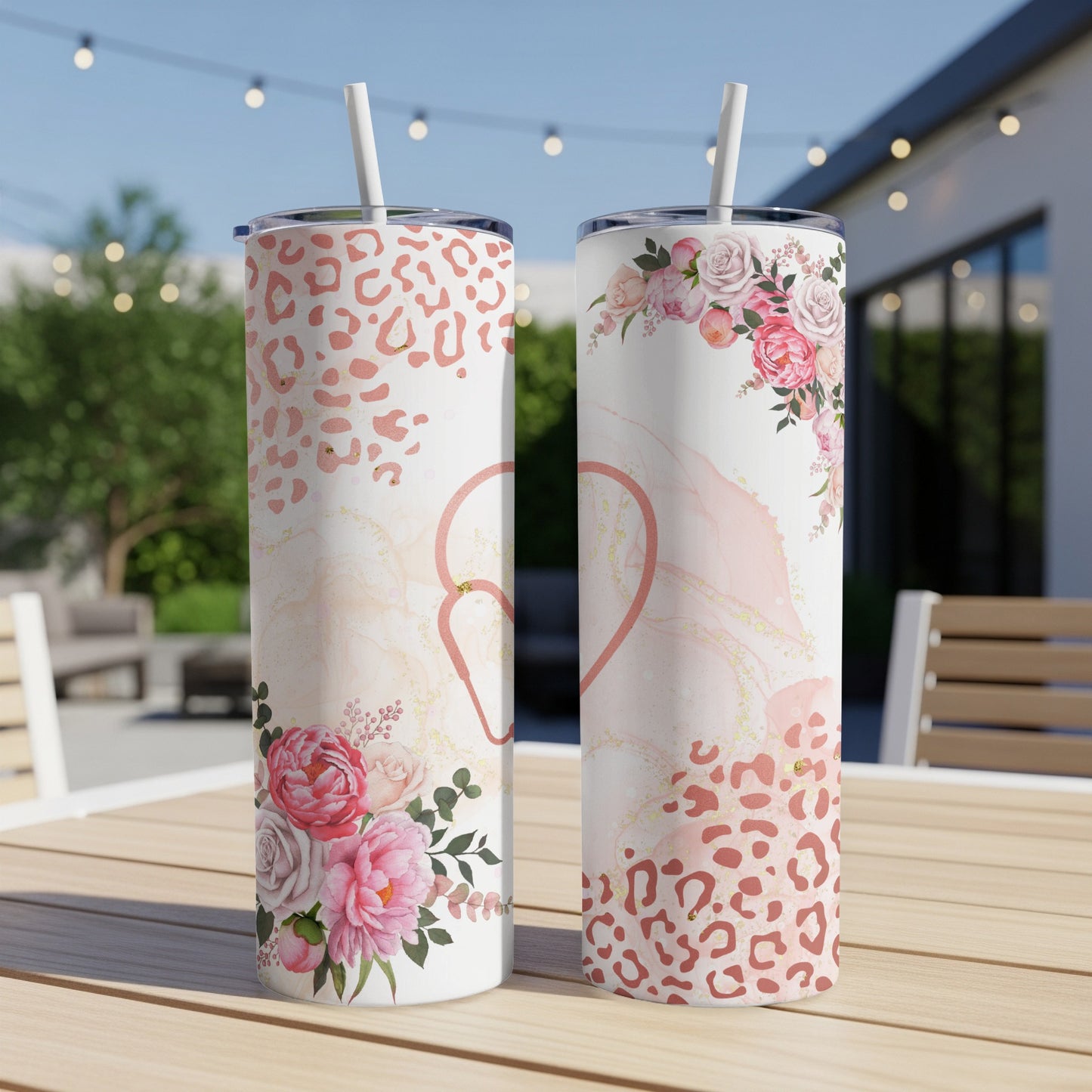 Two tumblers with floral and leopard print designs on a wooden table.