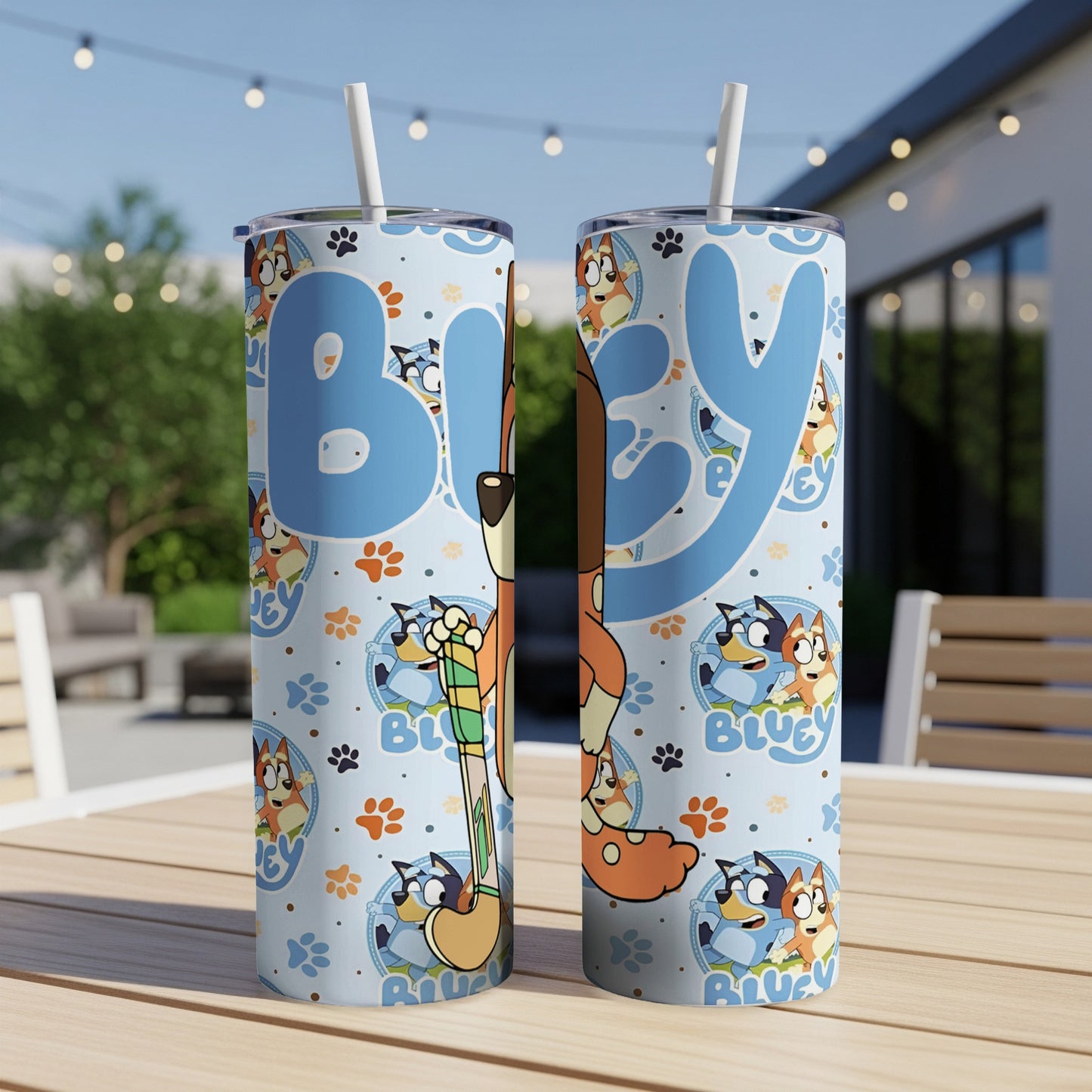 Two blue, character-themed tumblers with straws on a wooden table.