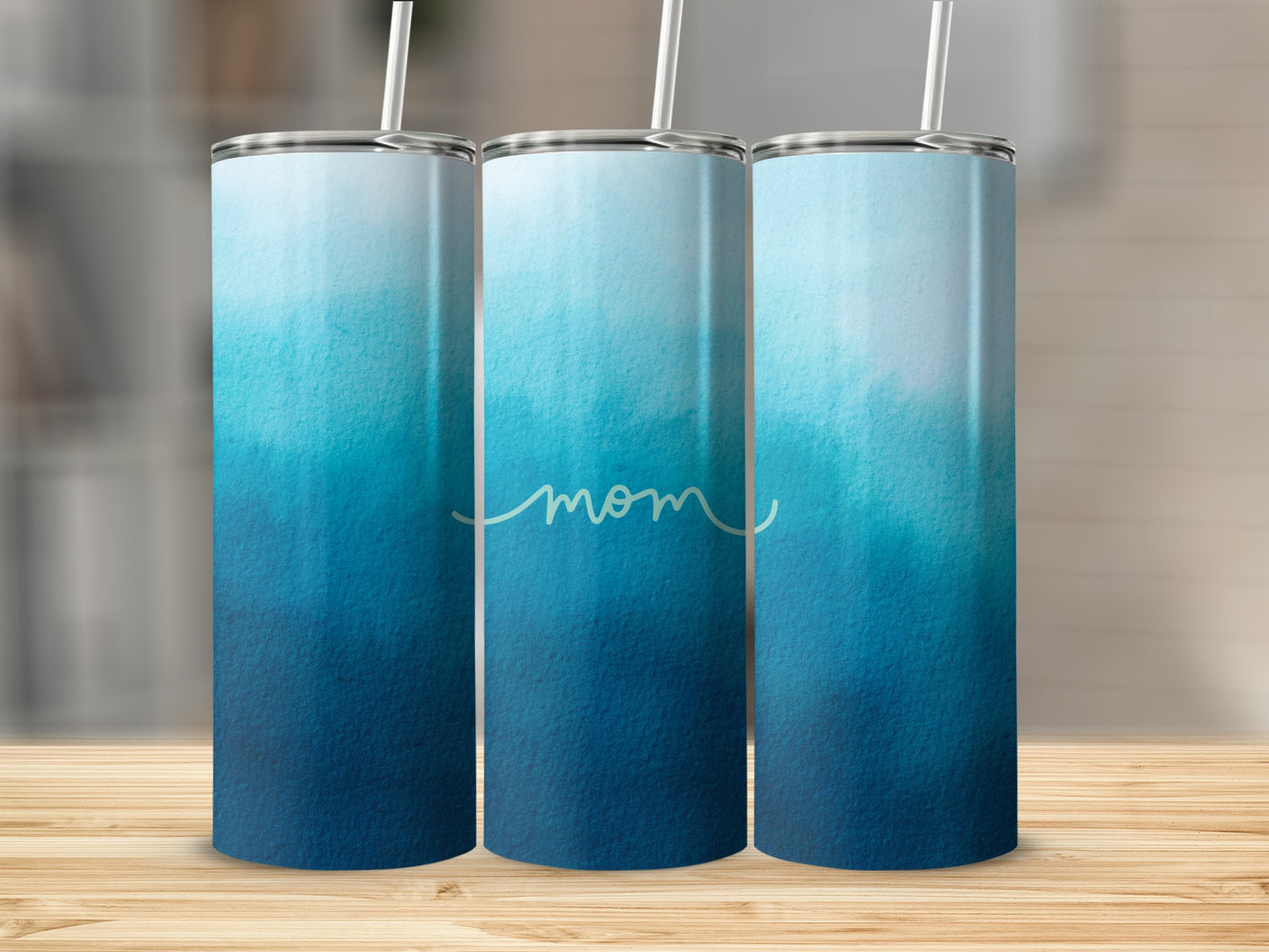 Three tumblers with a blue ombre watercolor design and "mom" text.