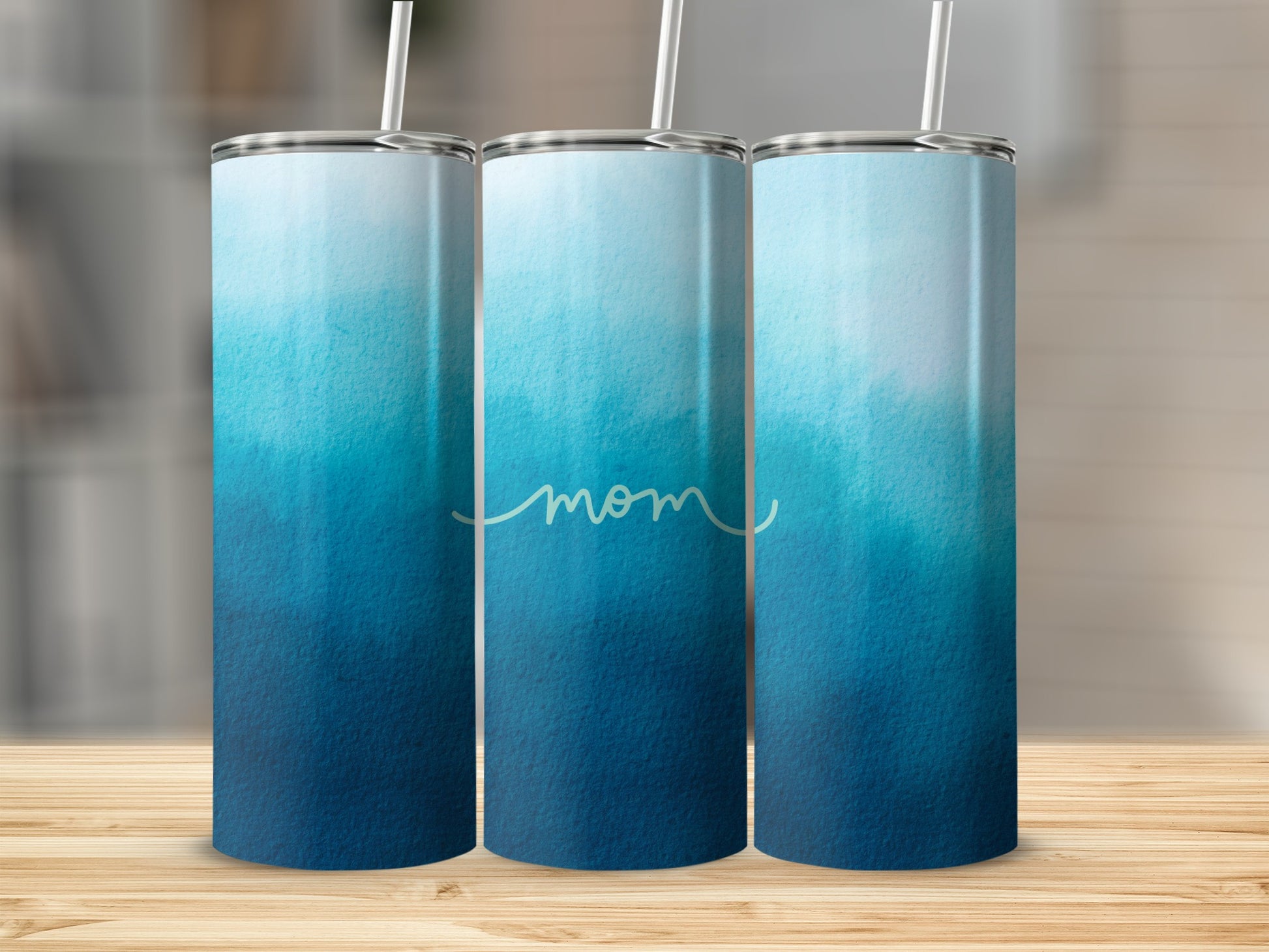 Three tumblers with a blue ombre watercolor design and "mom" text.