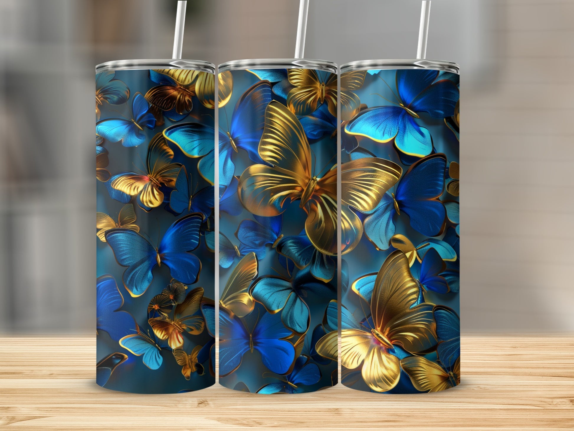 Blue and gold butterflies on three tumblers with straws, on a wooden surface.