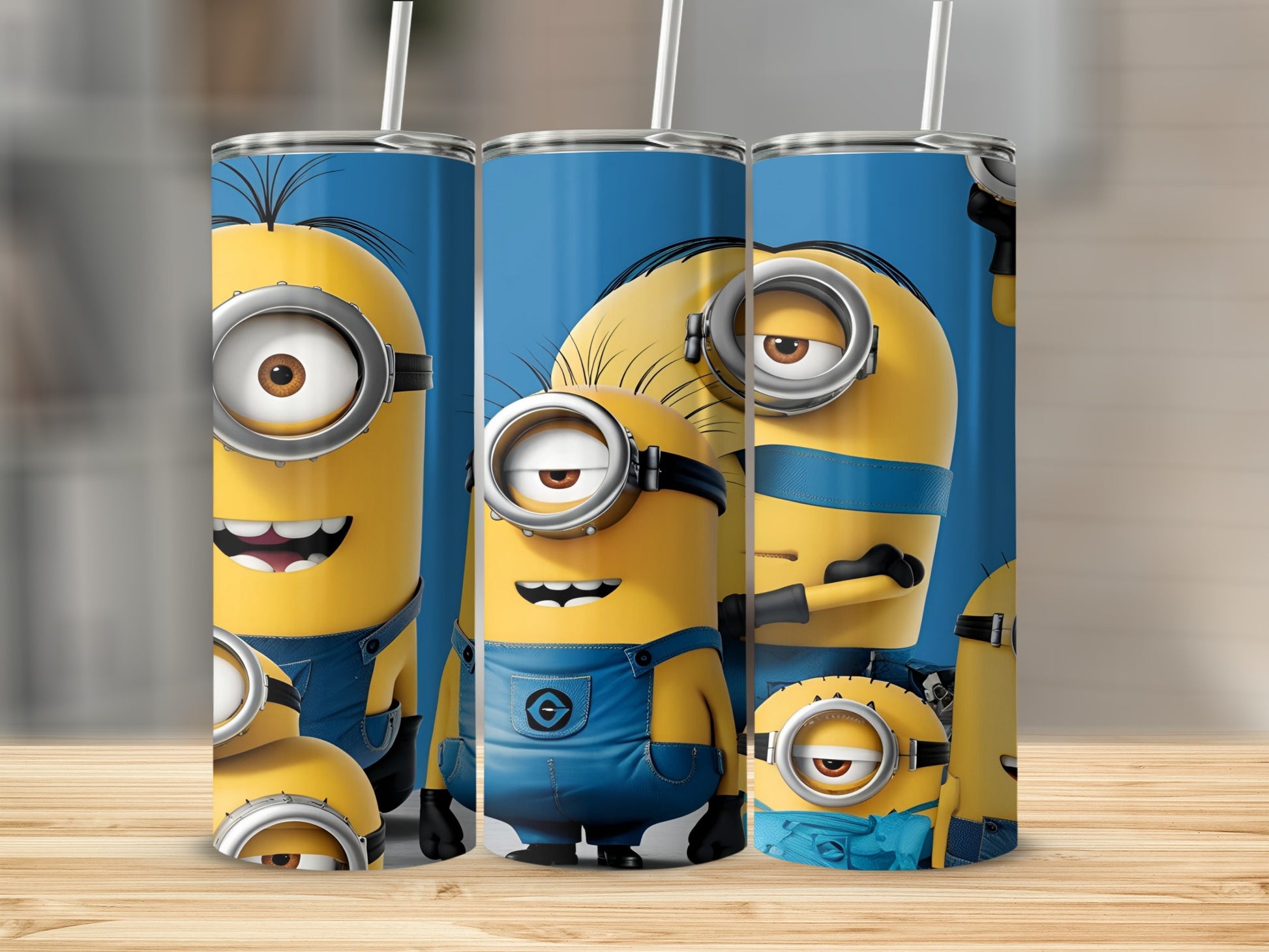 Three Minions on blue tumblers with straws on a wooden surface.