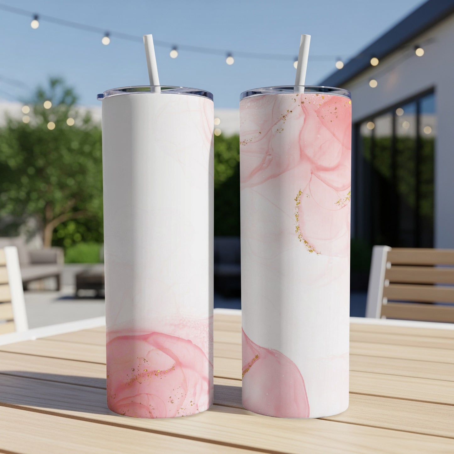 Two white tumblers with pink marble and gold glitter design on a table.
