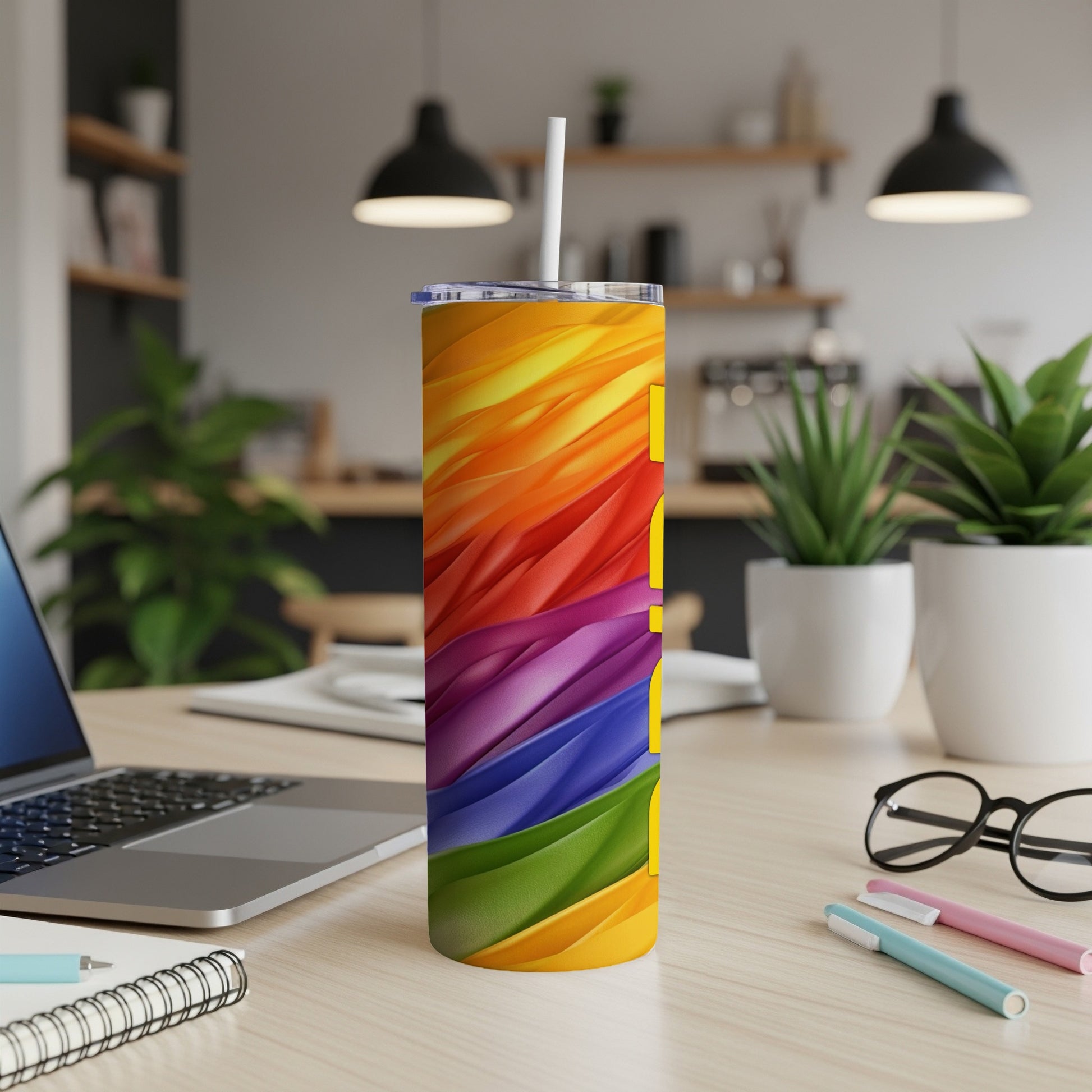 Rainbow gradient tumbler with white straw on a desk with laptop and pens.