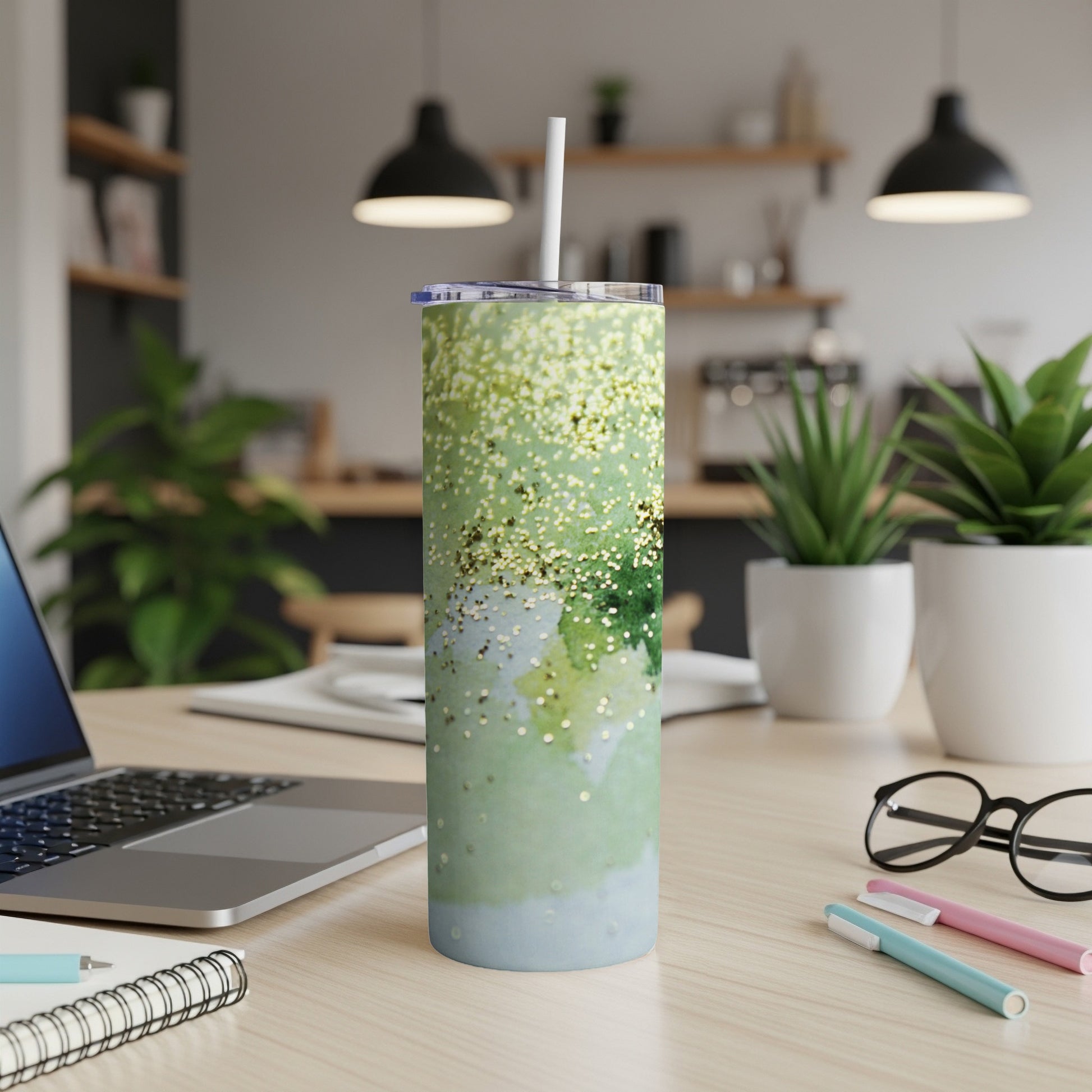Green glitter and watercolor textured tumbler with straw on desk.