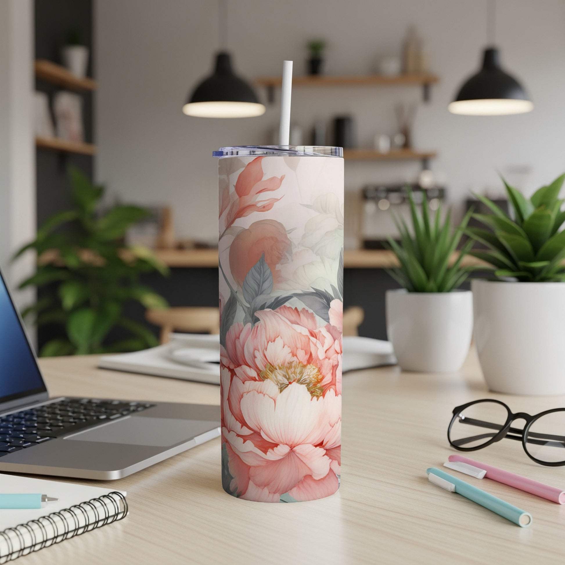 Pink floral pattern tumbler with straw on a desk with a laptop.