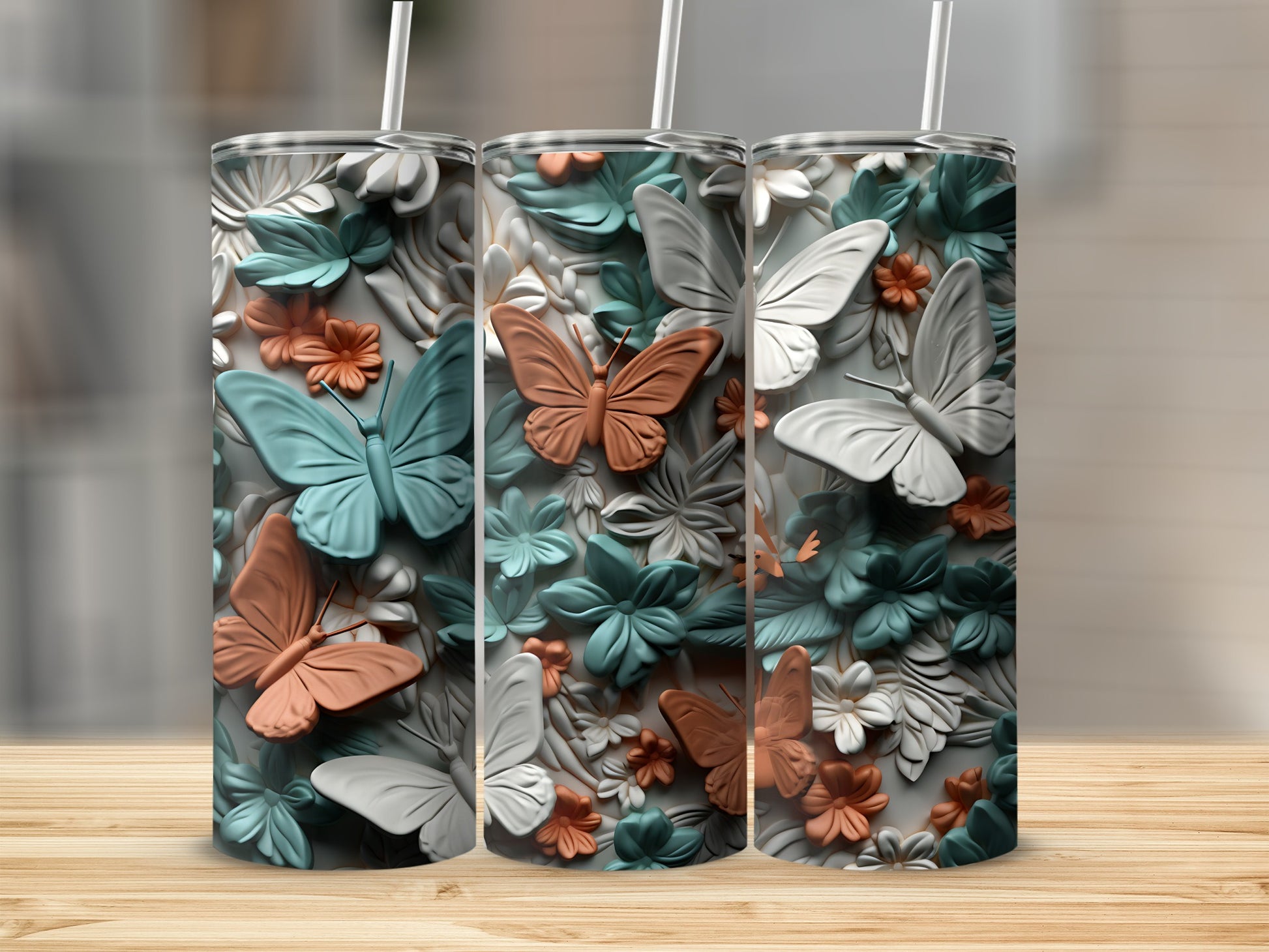 Three floral patterned tumblers with butterflies on a wooden surface.